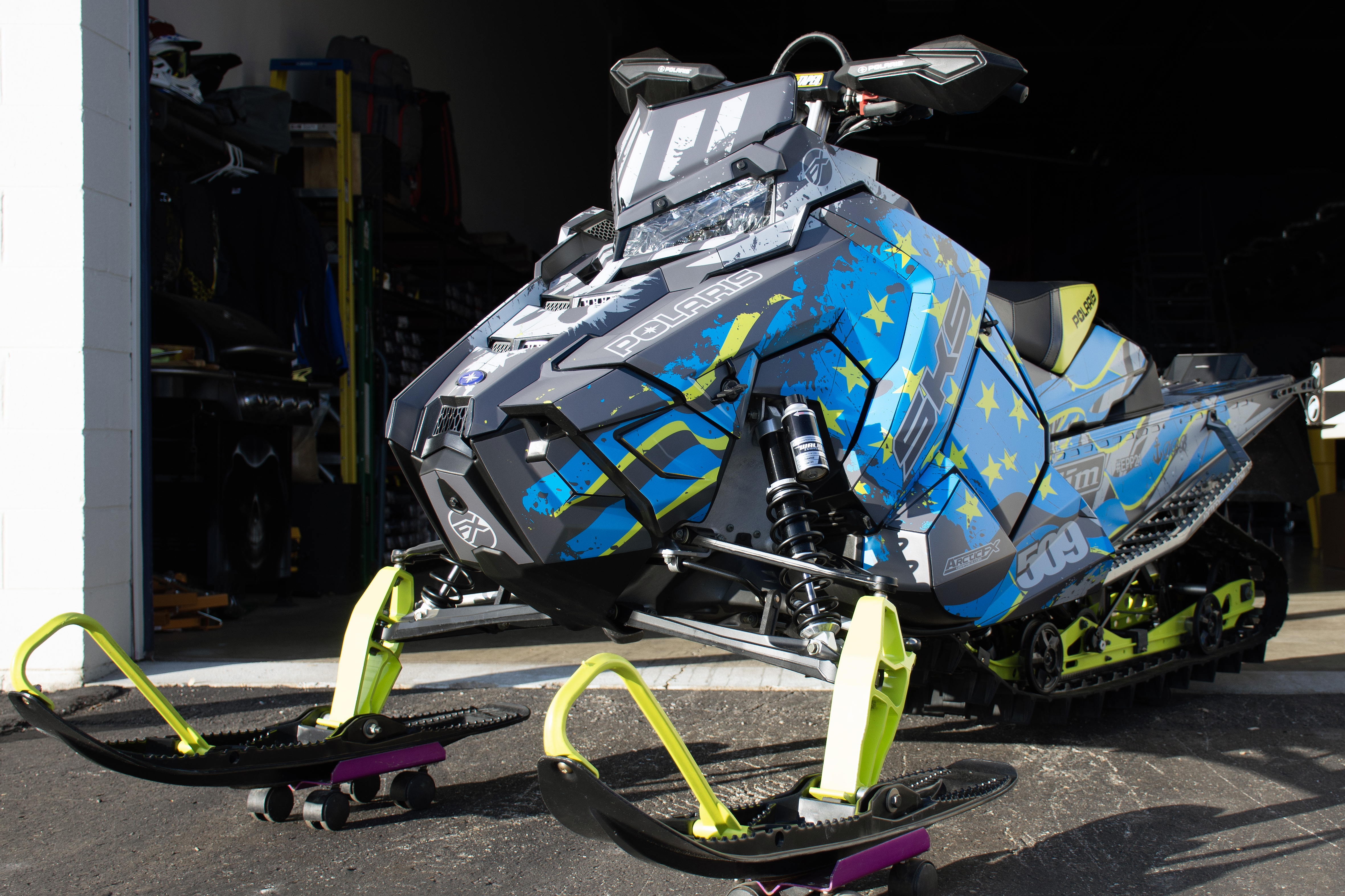 A Polaris Axys Crossover snowmobile with a lime squeeze, gray, and blue grunge American Flag custom vinyl wrap.