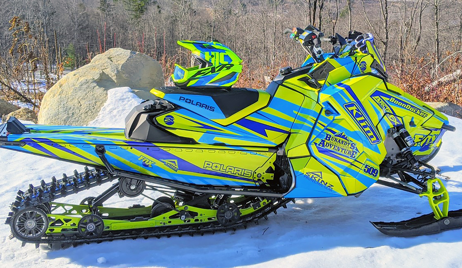 A Polaris Axys Crossover snowmobile with a lime squeeze and blue stripes Burandt Evolution custom vinyl wrap.