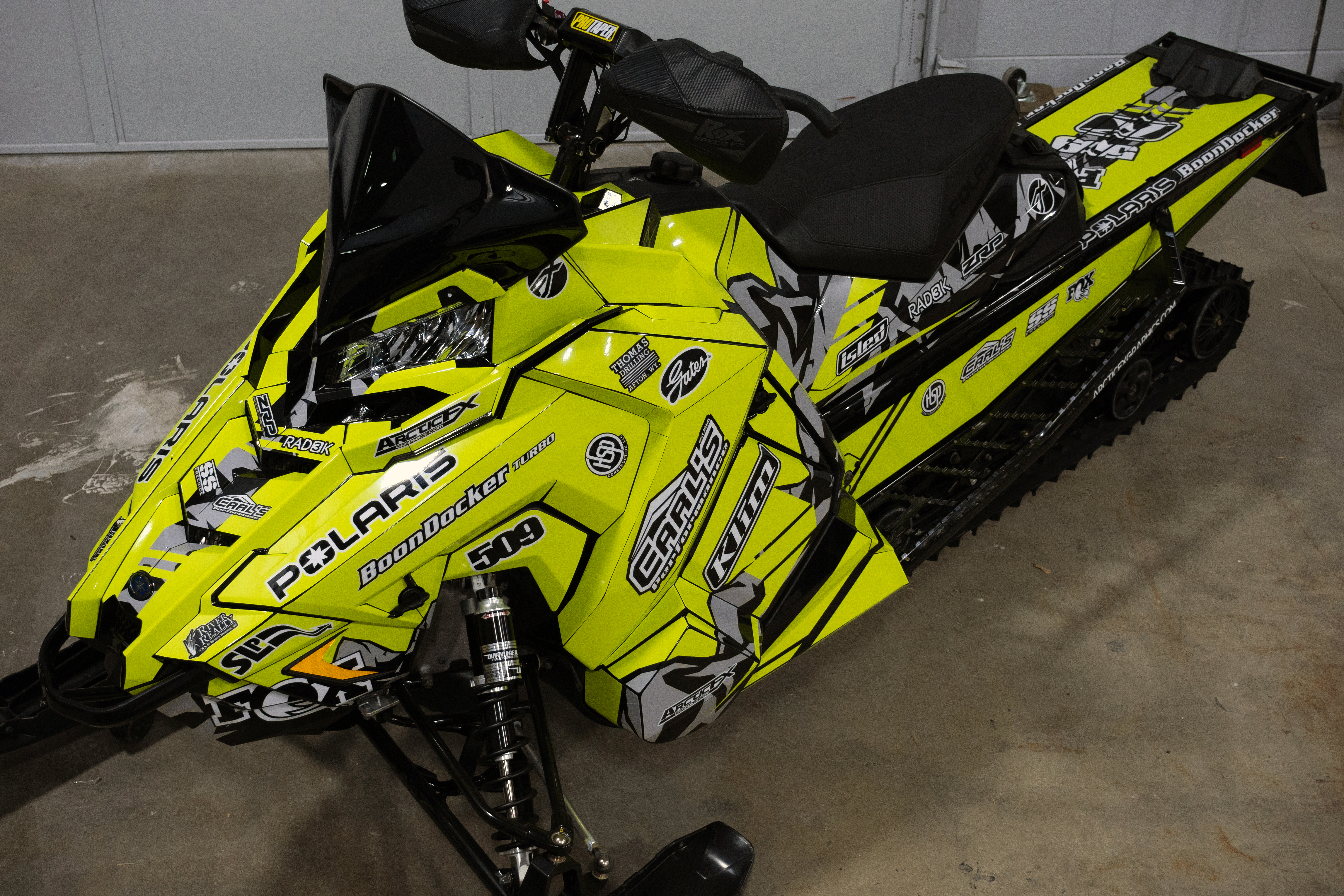 A Polaris Axys Crossover snowmobile with a lime squeeze, gray, and black mountain stripes Burandt Vista custom vinyl wrap.