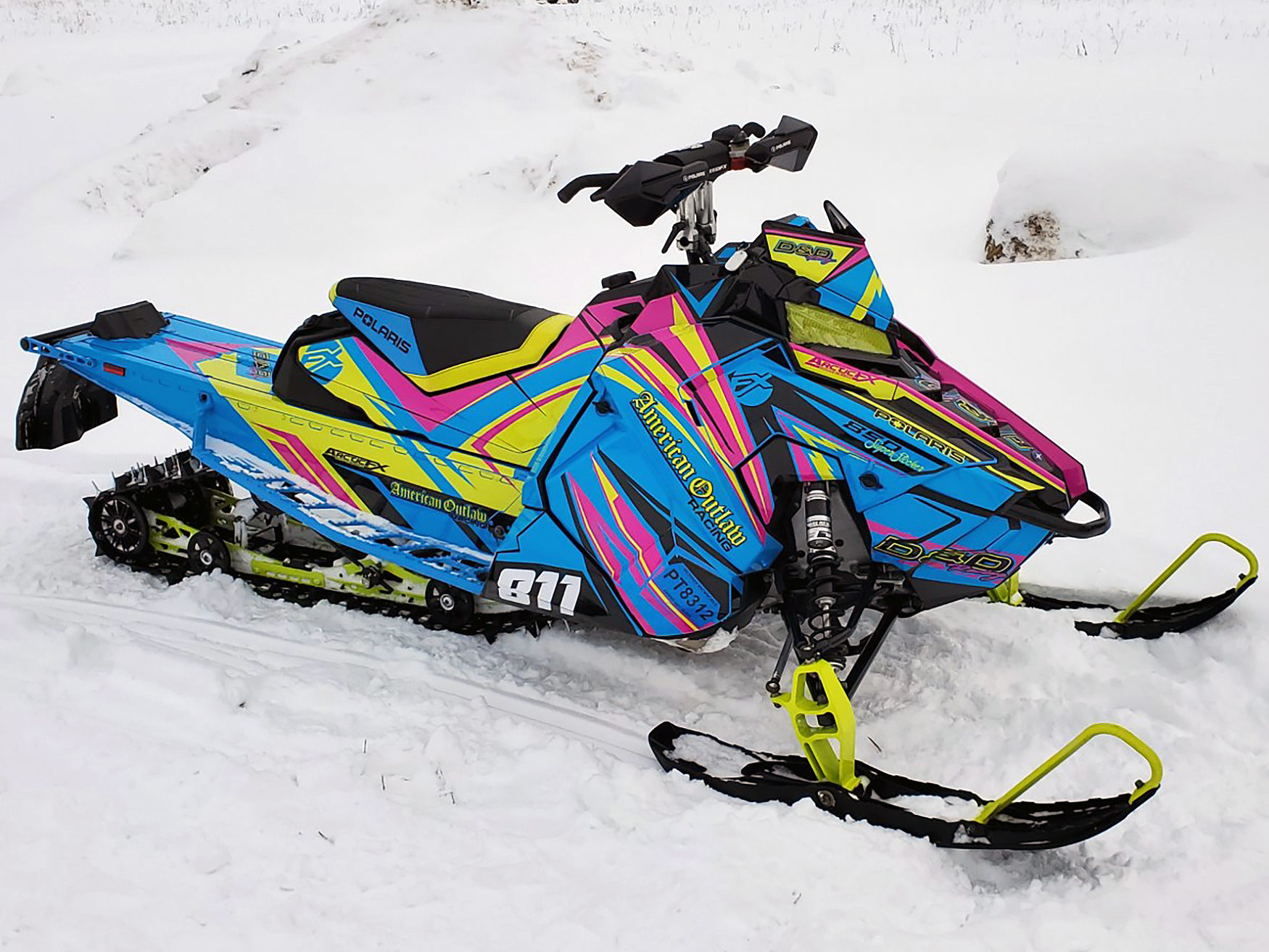 A Polaris Axys Crossover snowmobile with a lime squeeze, pink, and blue stripes Kesterke Adrenaline custom vinyl wrap.