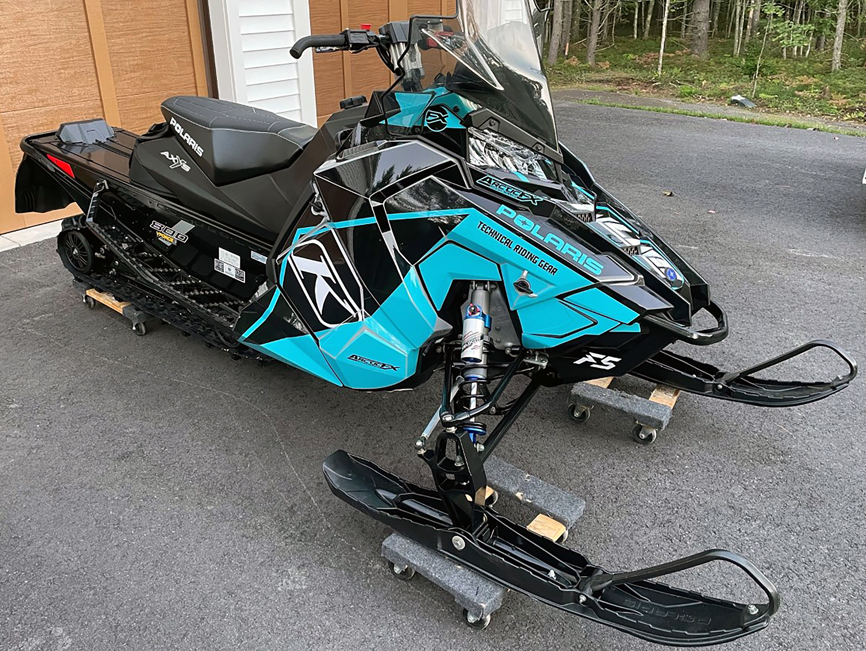 A Polaris Axys Crossover snowmobile with a blue, white, and black Klim F5 Ion custom vinyl wrap.