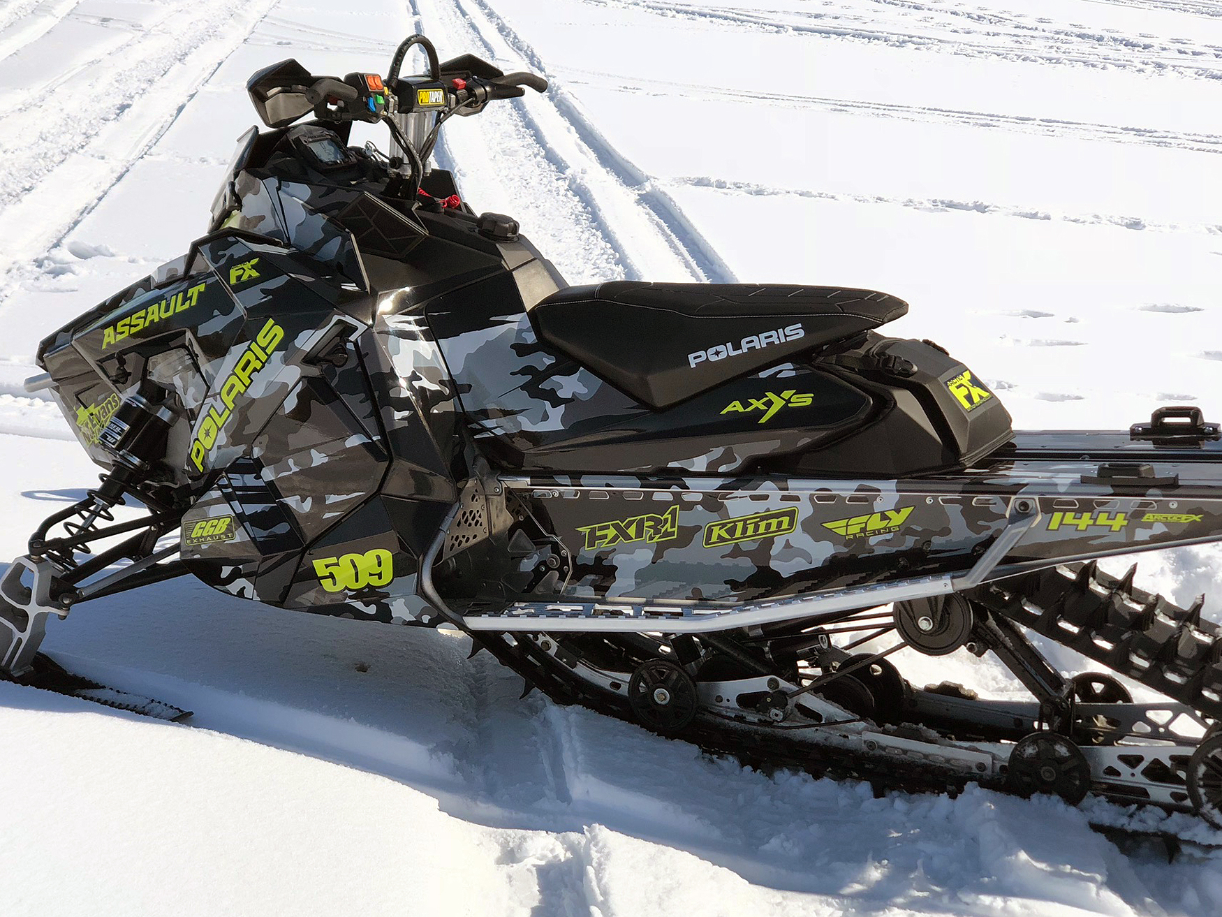 A Polaris Axys Crossover snowmobile with a lime squeeze, black, and gray grunge RR Camo custom vinyl wrap.