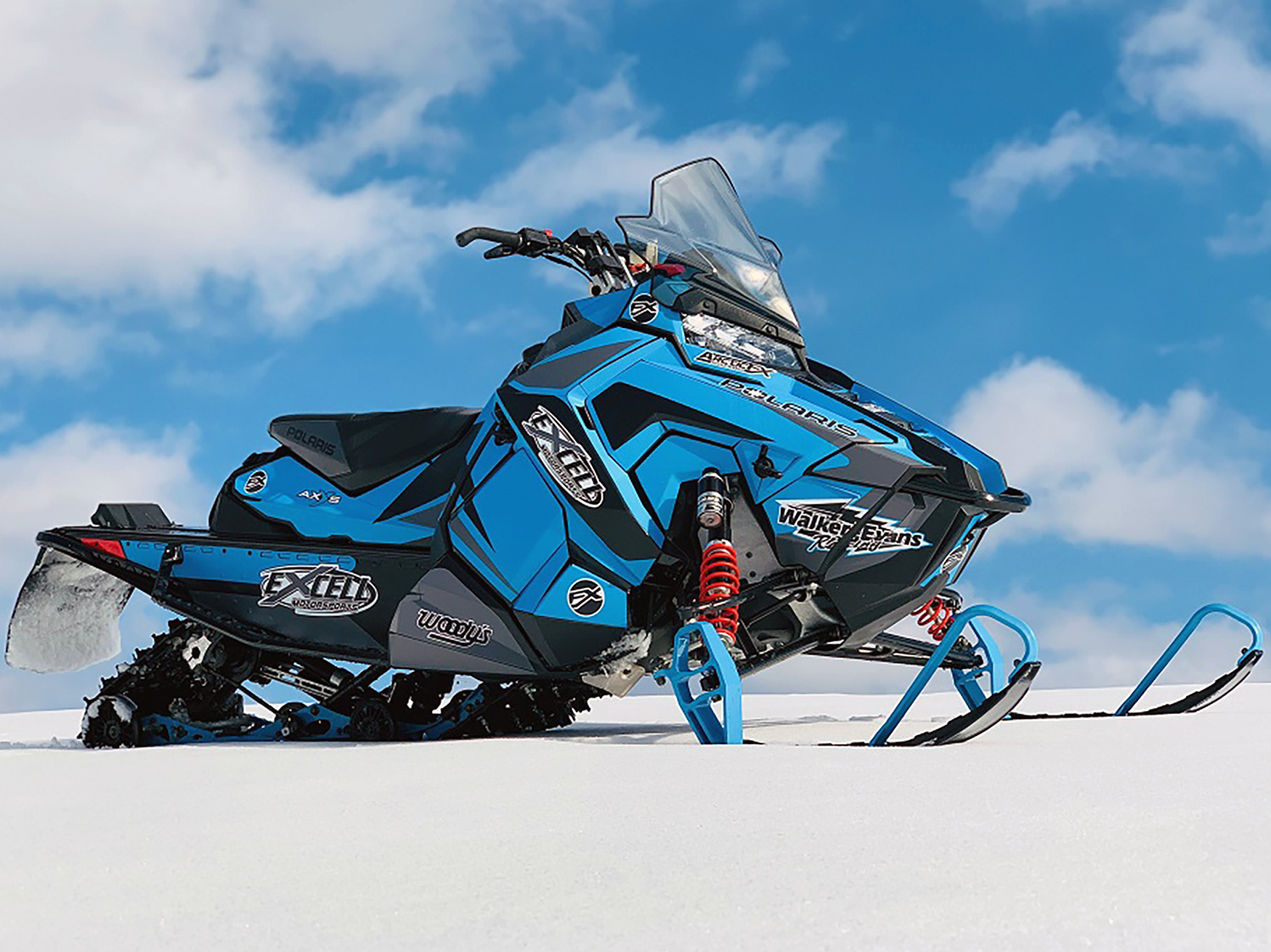 A Polaris Axys Crossover snowmobile with a white, black, and blue Justin Thomas Velocity custom vinyl wrap.