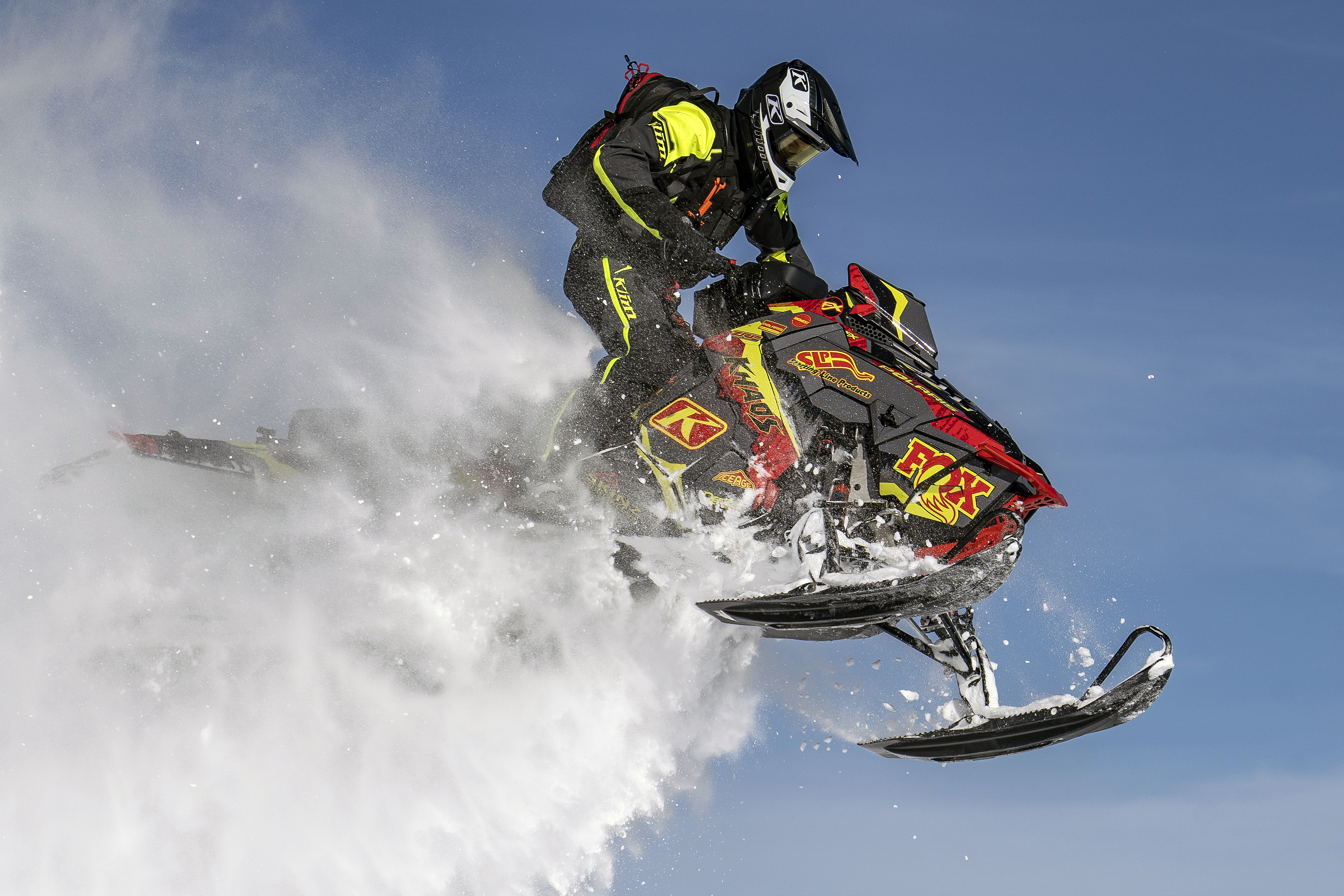 A Polaris Axys Mountain snowmobile with a lime squeeze, red, and gray tribal Adams Alpine custom vinyl wrap.