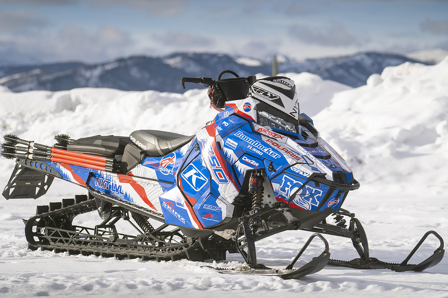 A Polaris Axys Mountain snowmobile with a red, white, and blue tribal Adams Alpine custom vinyl wrap.