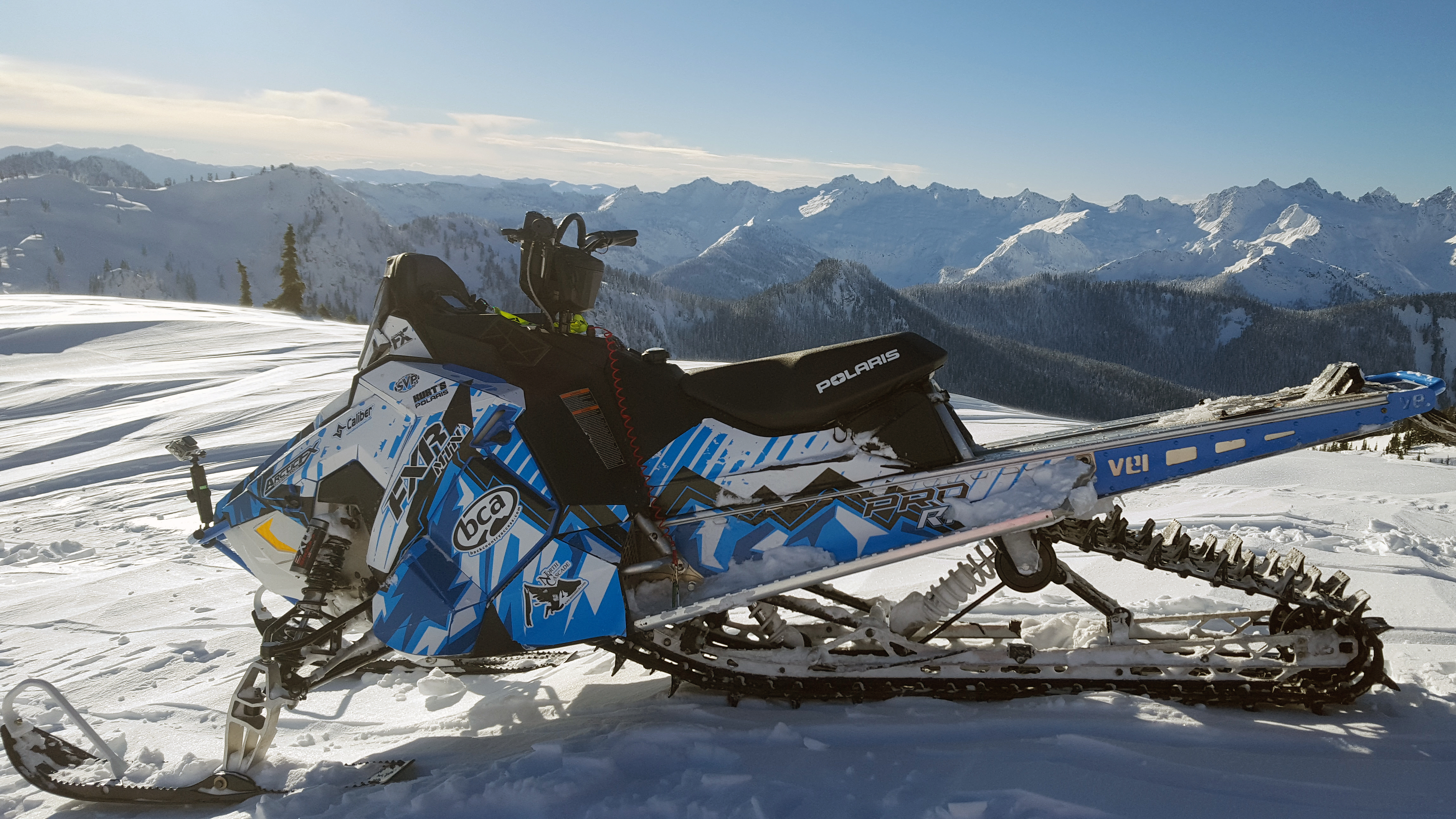 A Polaris Axys Mountain snowmobile with a black, white, and blue Altitude custom vinyl wrap.