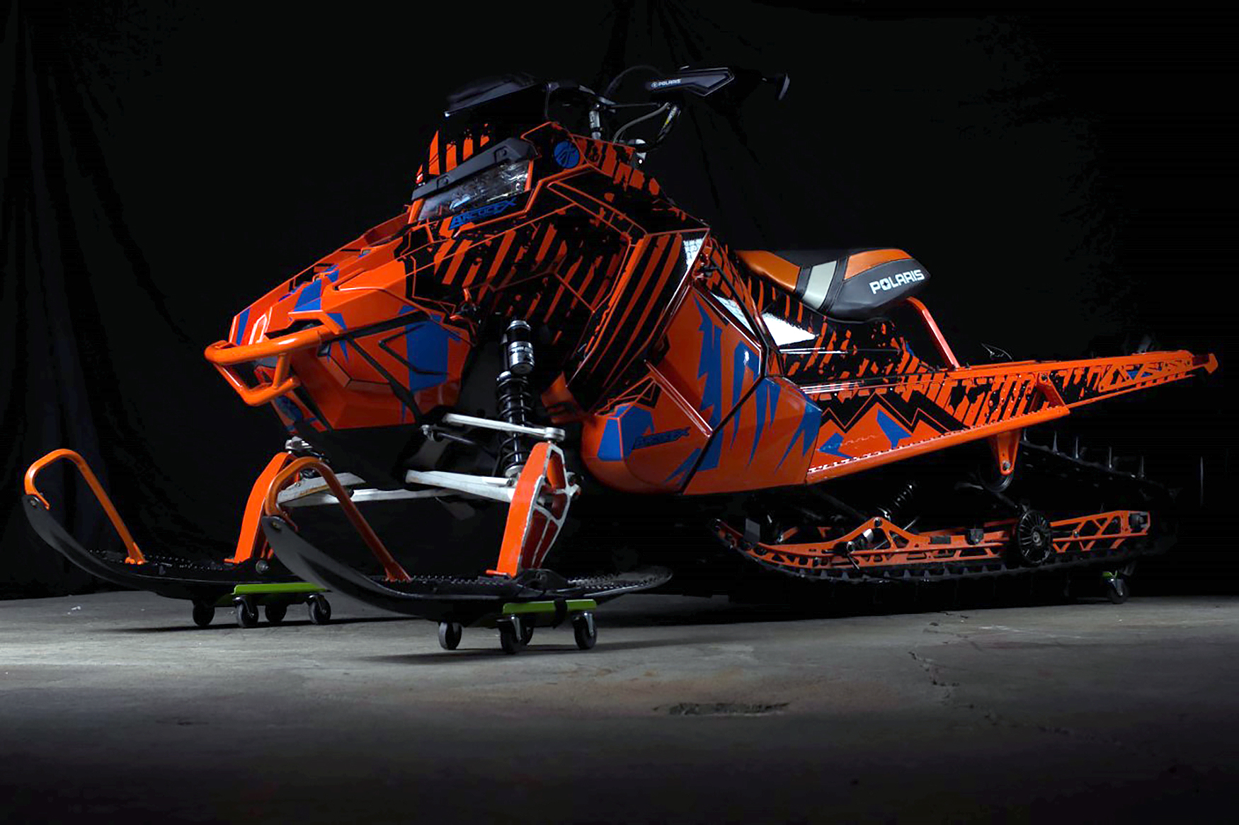 A Polaris Axys Mountain snowmobile with a orange, blue, and black Altitude custom vinyl wrap.