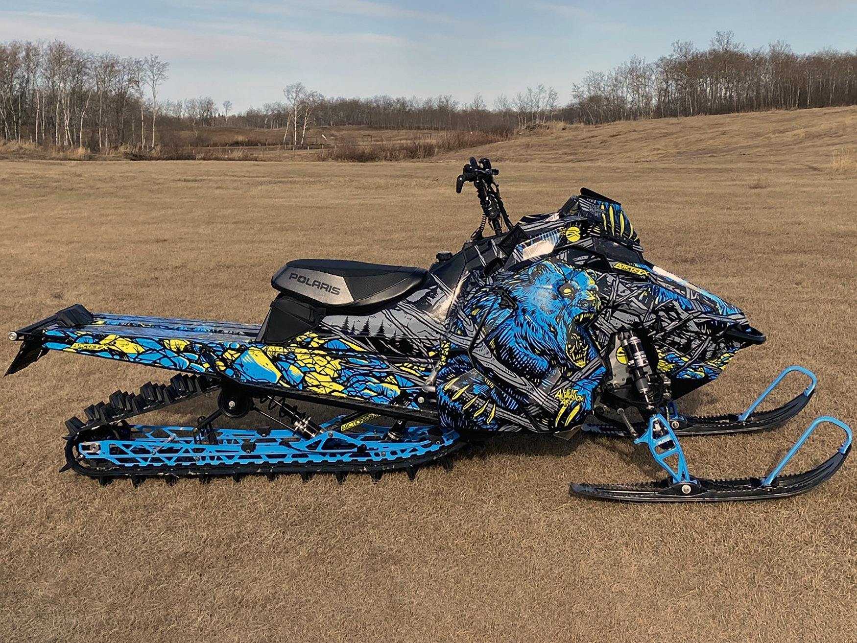 A Polaris Axys Mountain snowmobile with a lime squeeze, blue, and gray Leif Alvarsson Kodiak custom vinyl wrap.