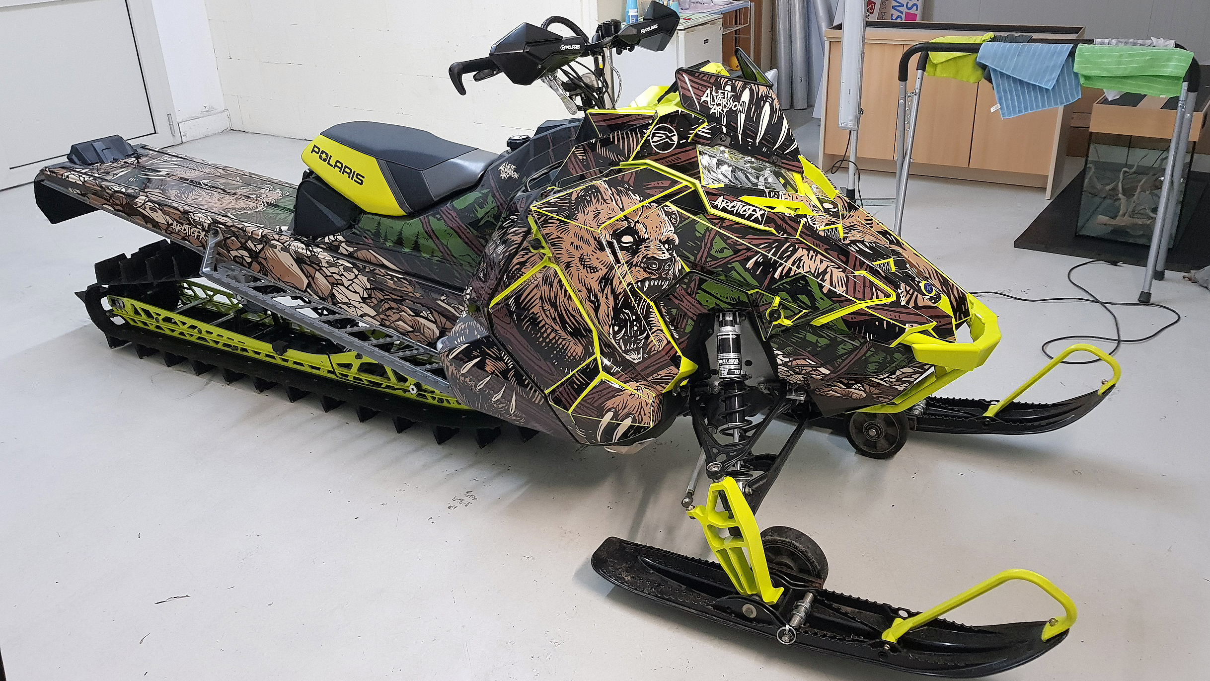 A Polaris Axys Mountain snowmobile with a brown, green, and black Leif Alvarsson Kodiak custom vinyl wrap.