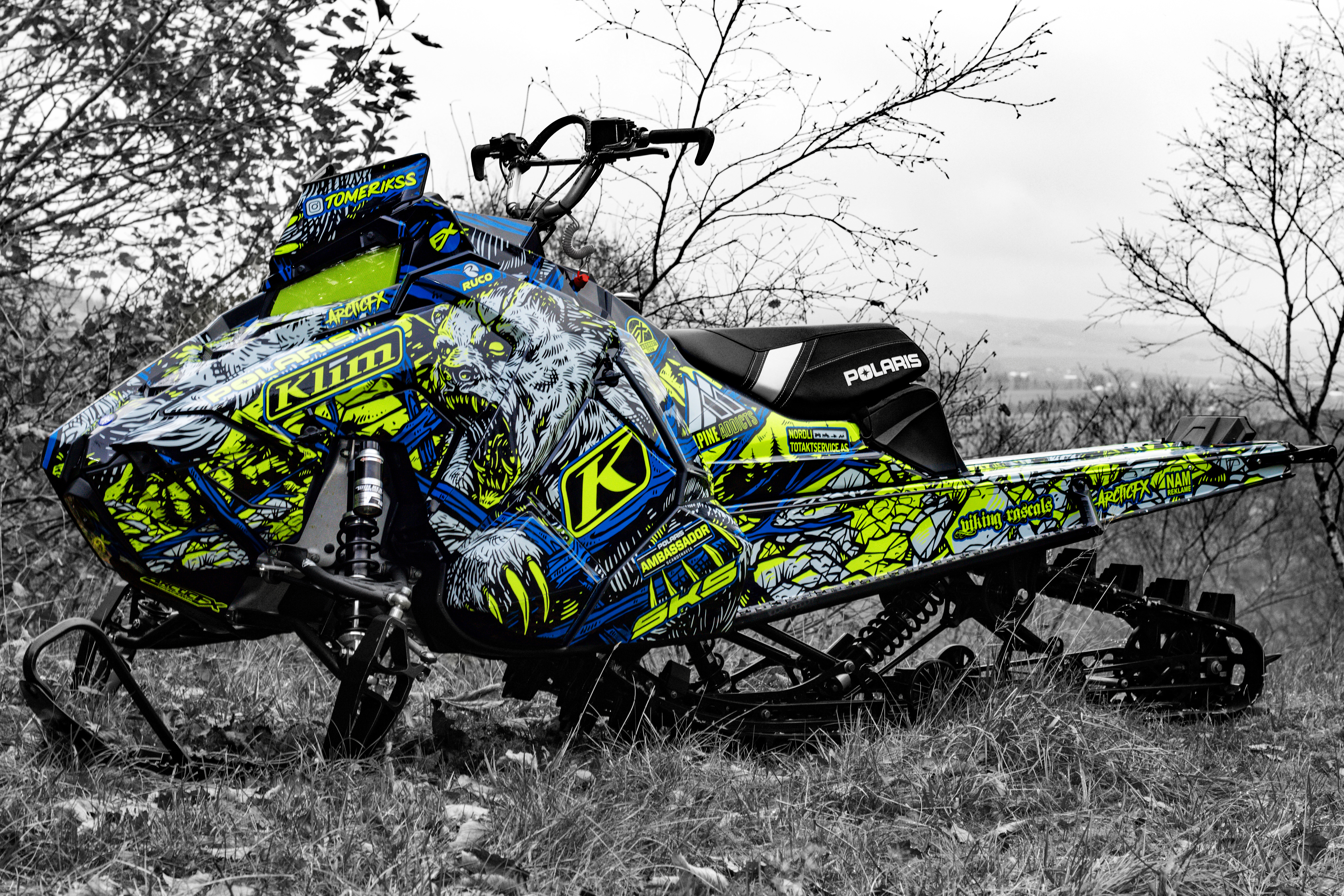 A Polaris Axys Mountain snowmobile with a lime squeeze, blue, and black Leif Alvarsson Kodiak custom vinyl wrap.