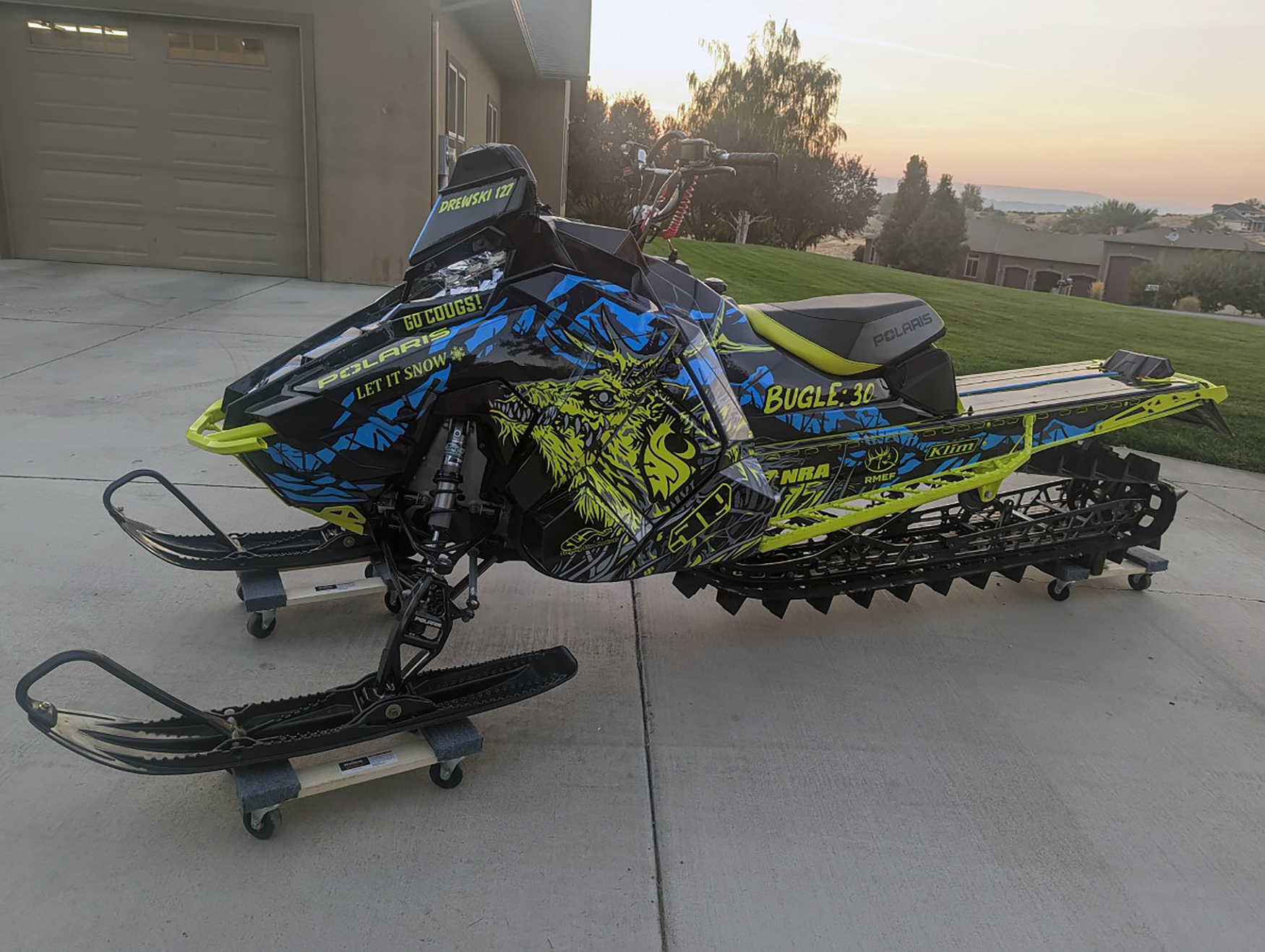 A Polaris Axys Mountain snowmobile with a lime squeeze, blue, and black Leif Alvarsson Specter custom vinyl wrap.