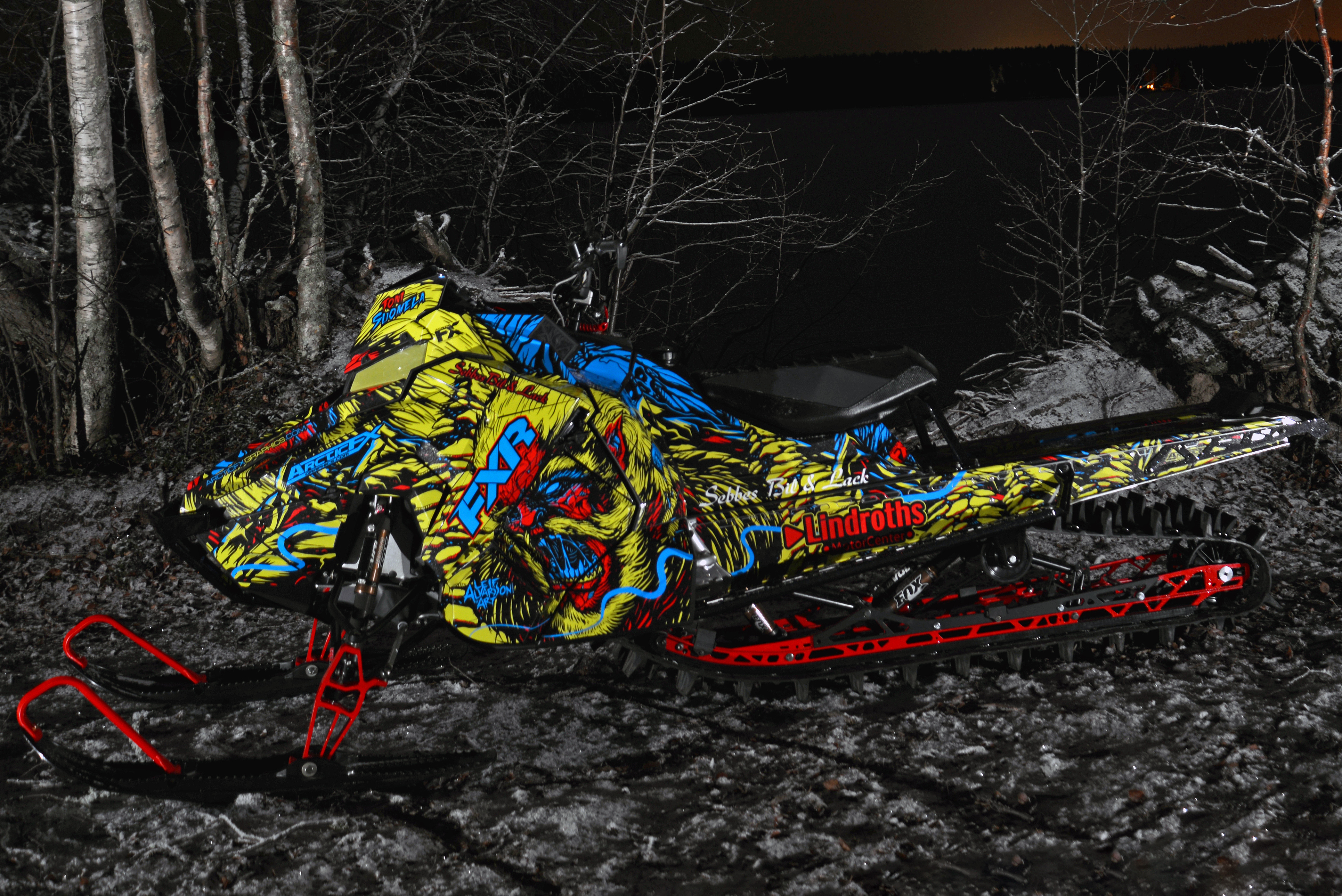 A Polaris Axys Mountain snowmobile with a lime squeeze, blue, and red Leif Alvarsson Tree Slayer custom vinyl wrap.