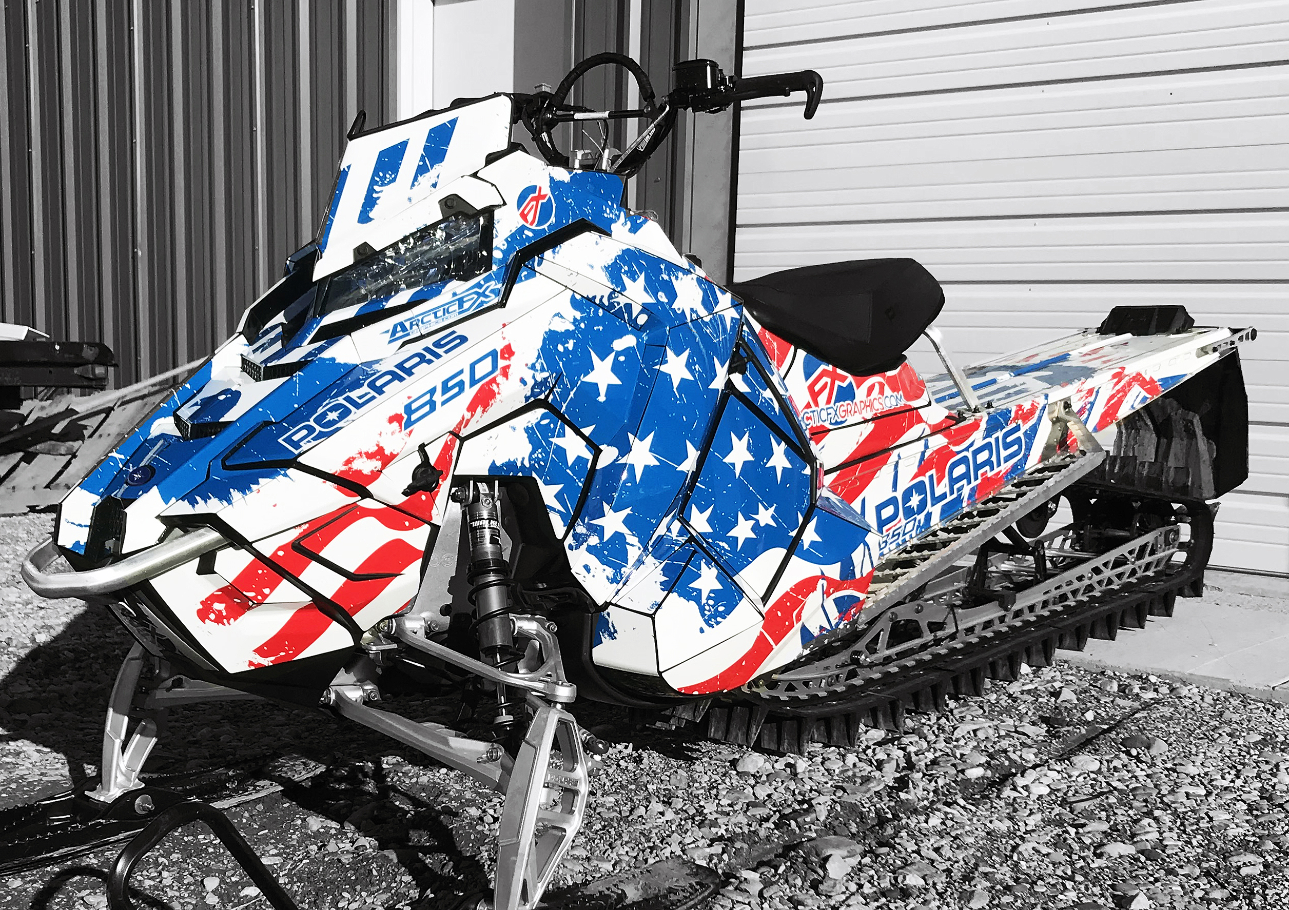A Polaris Axys Mountain snowmobile with a red, white, and blue grunge American Flag custom vinyl wrap.