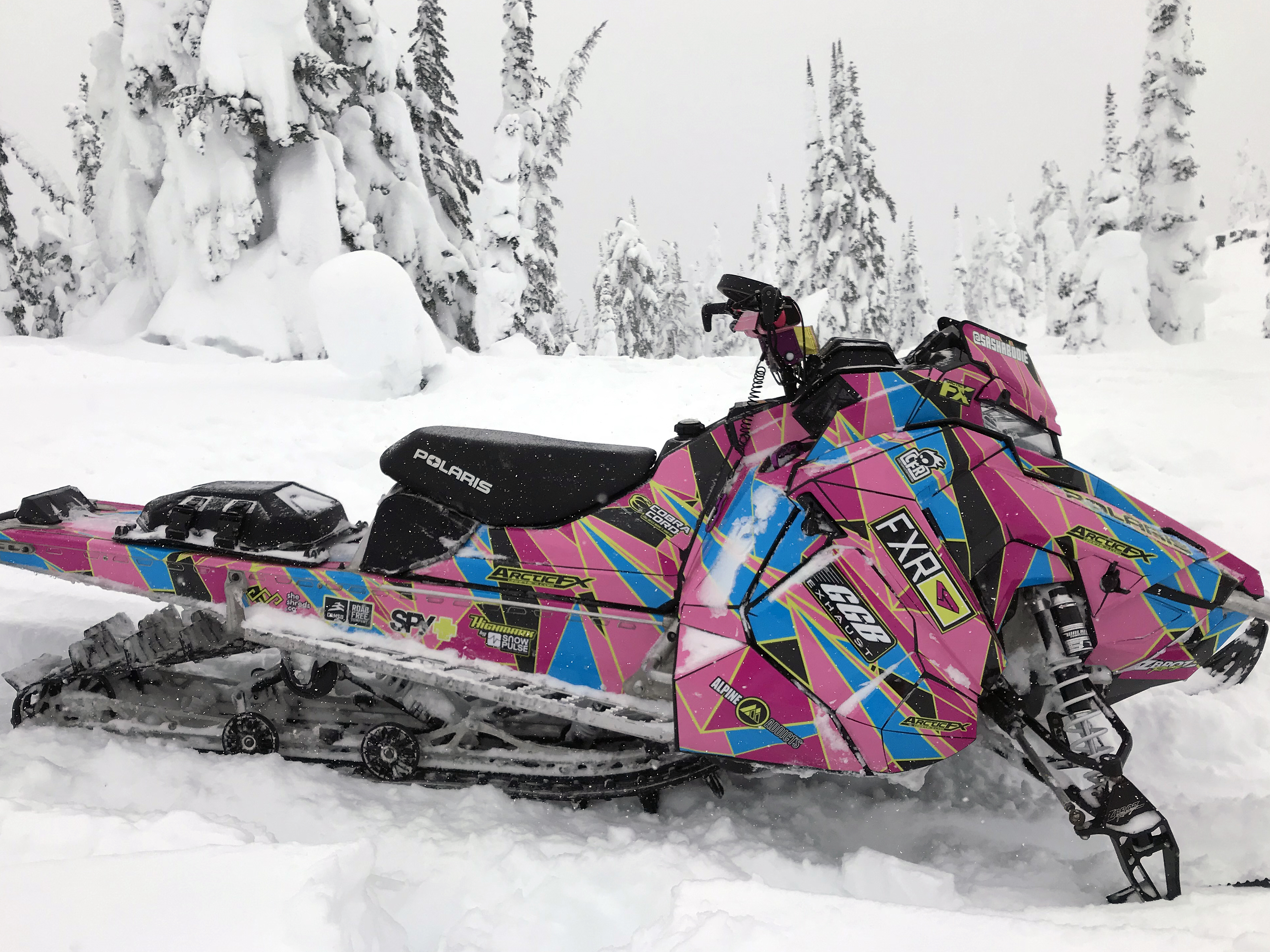 A Polaris Axys Mountain snowmobile with a lime squeeze, pink, and blue grunge Ascension custom vinyl wrap.