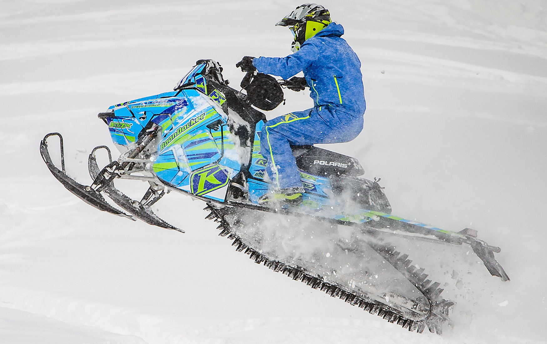 A Polaris Axys Mountain snowmobile with a lime, blue, and cyan blue stripes Burandt Evolution custom vinyl wrap.