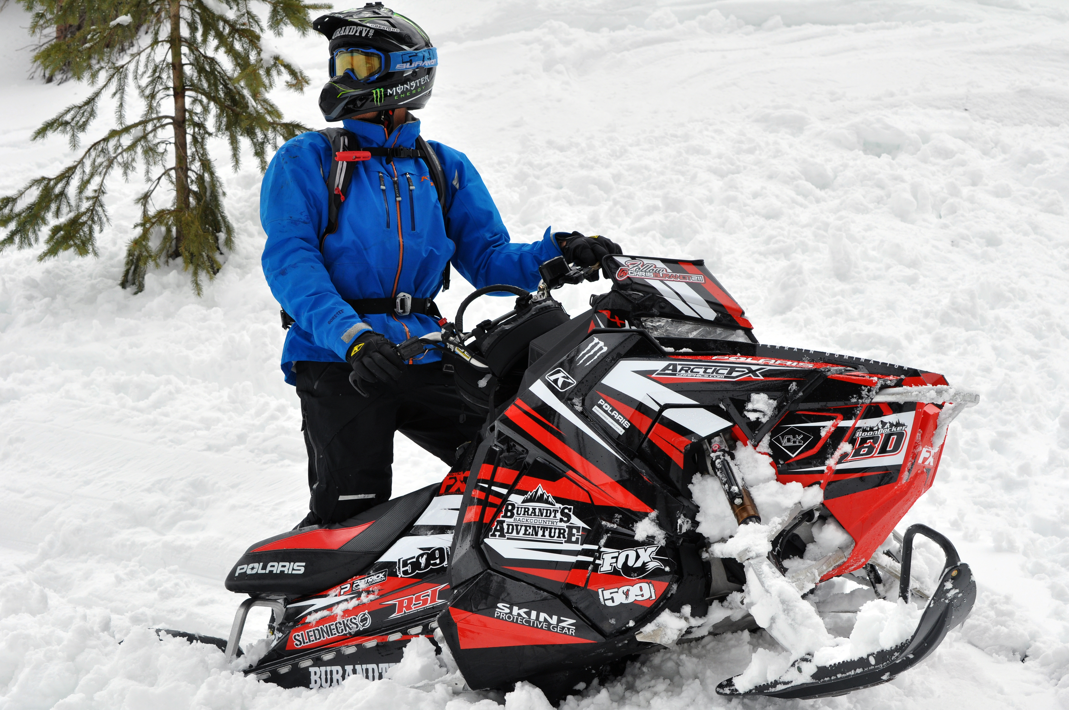 A Polaris Axys Mountain snowmobile with a red, black, and white stripes Burandt Evolution custom vinyl wrap.