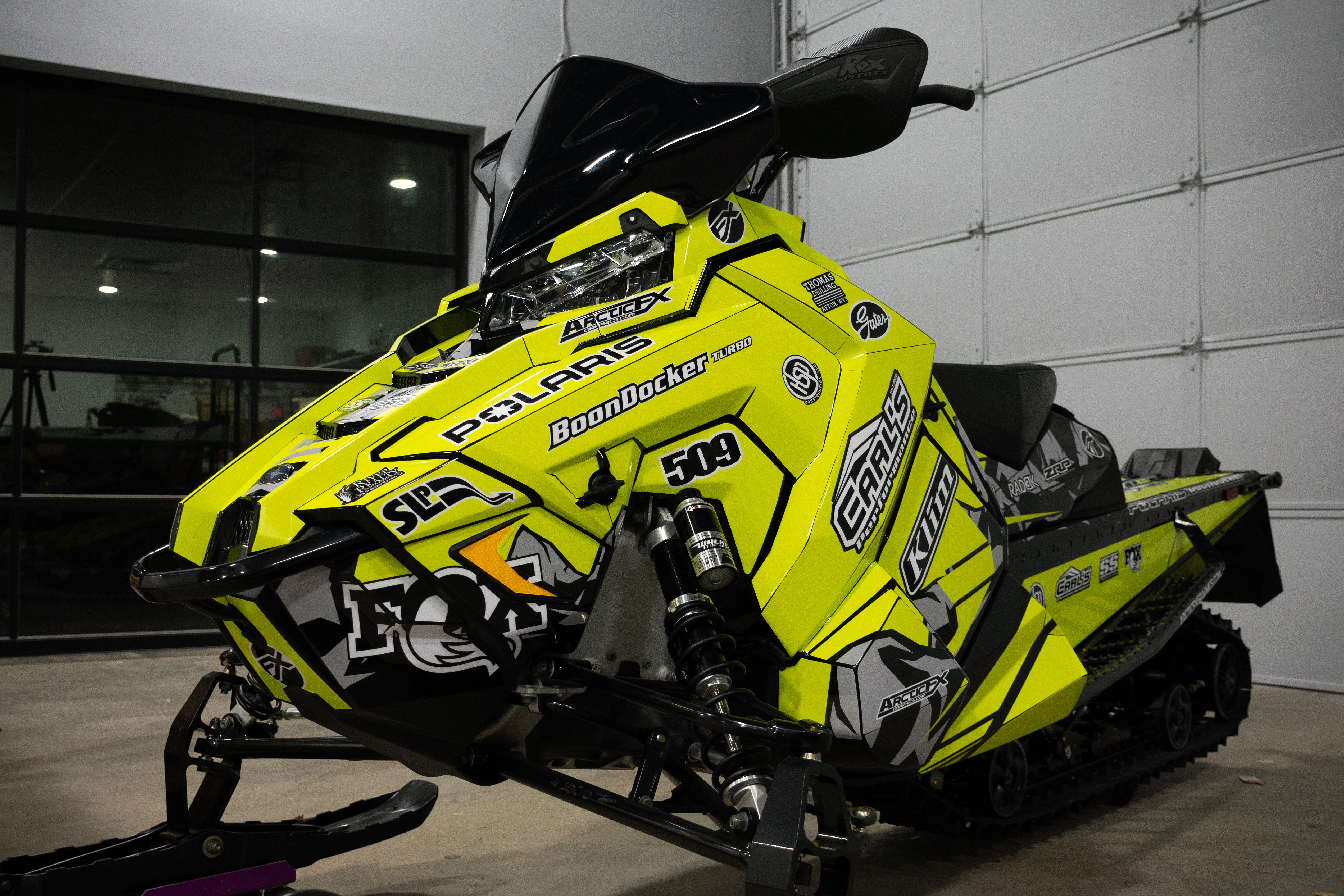 A Polaris Axys Mountain snowmobile with a lime squeeze, black, and gray Burandt Vista custom vinyl wrap.