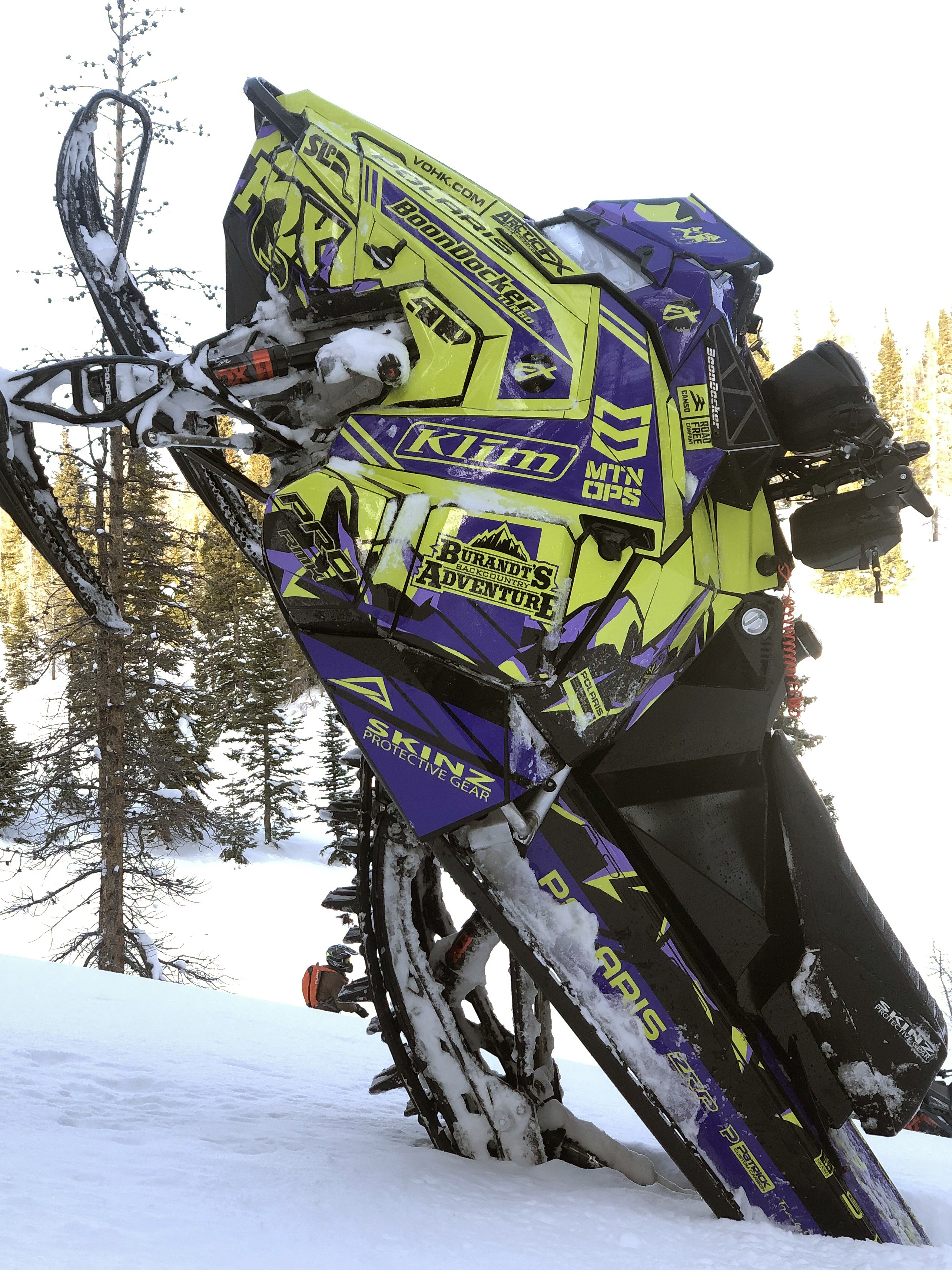 A Polaris Axys Mountain snowmobile with a lime squeeze, black, and purple Burandt Vista custom vinyl wrap.