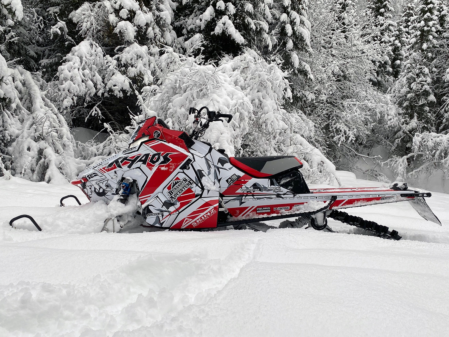 A Polaris Axys Mountain snowmobile with a red, black, and white Burandt Vista custom vinyl wrap.