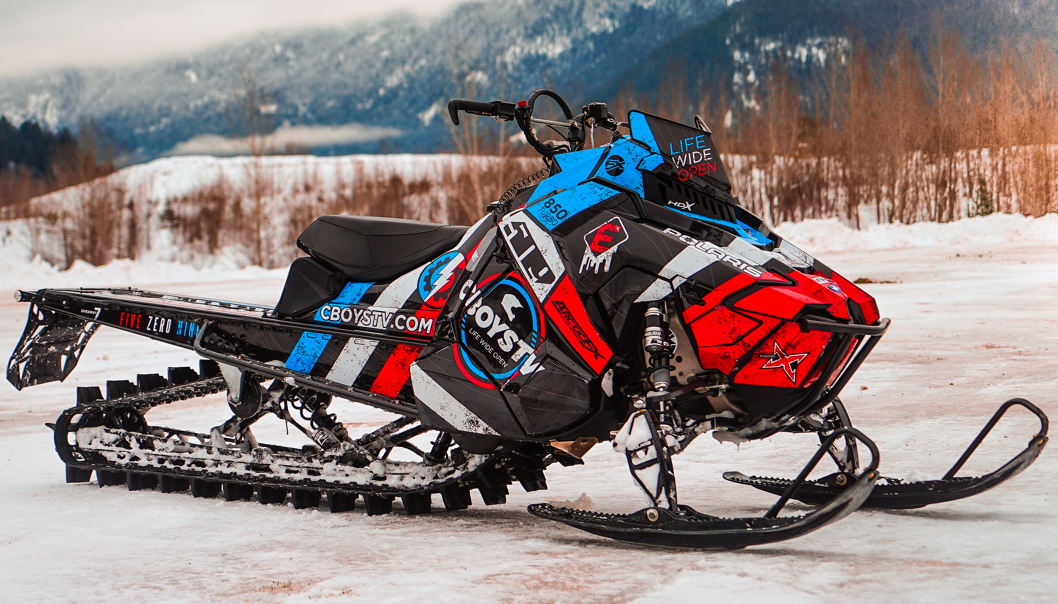A Polaris Axys Mountain snowmobile with a red, white, and blue Cboys TV custom vinyl wrap.