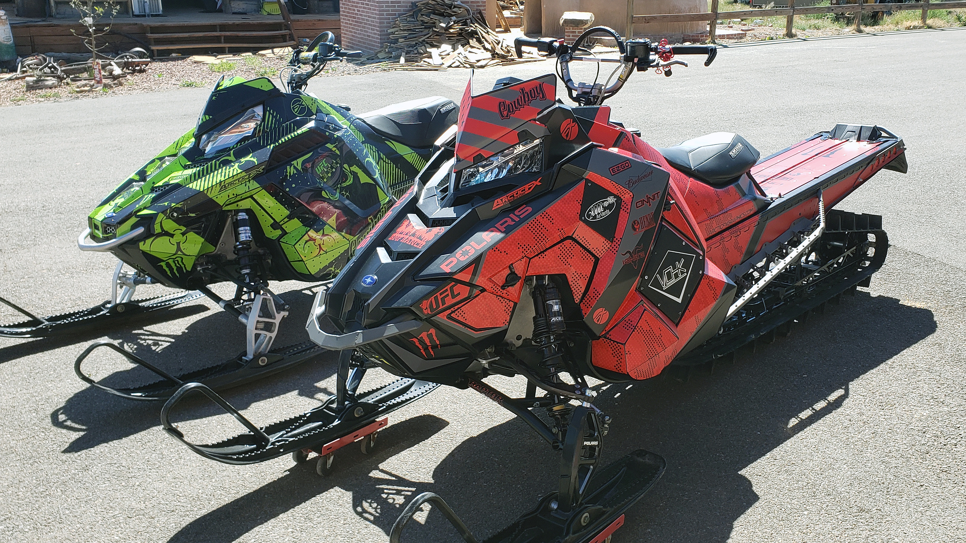 A Polaris Axys Mountain snowmobile with a red, gray, and black Cowboy custom vinyl wrap.