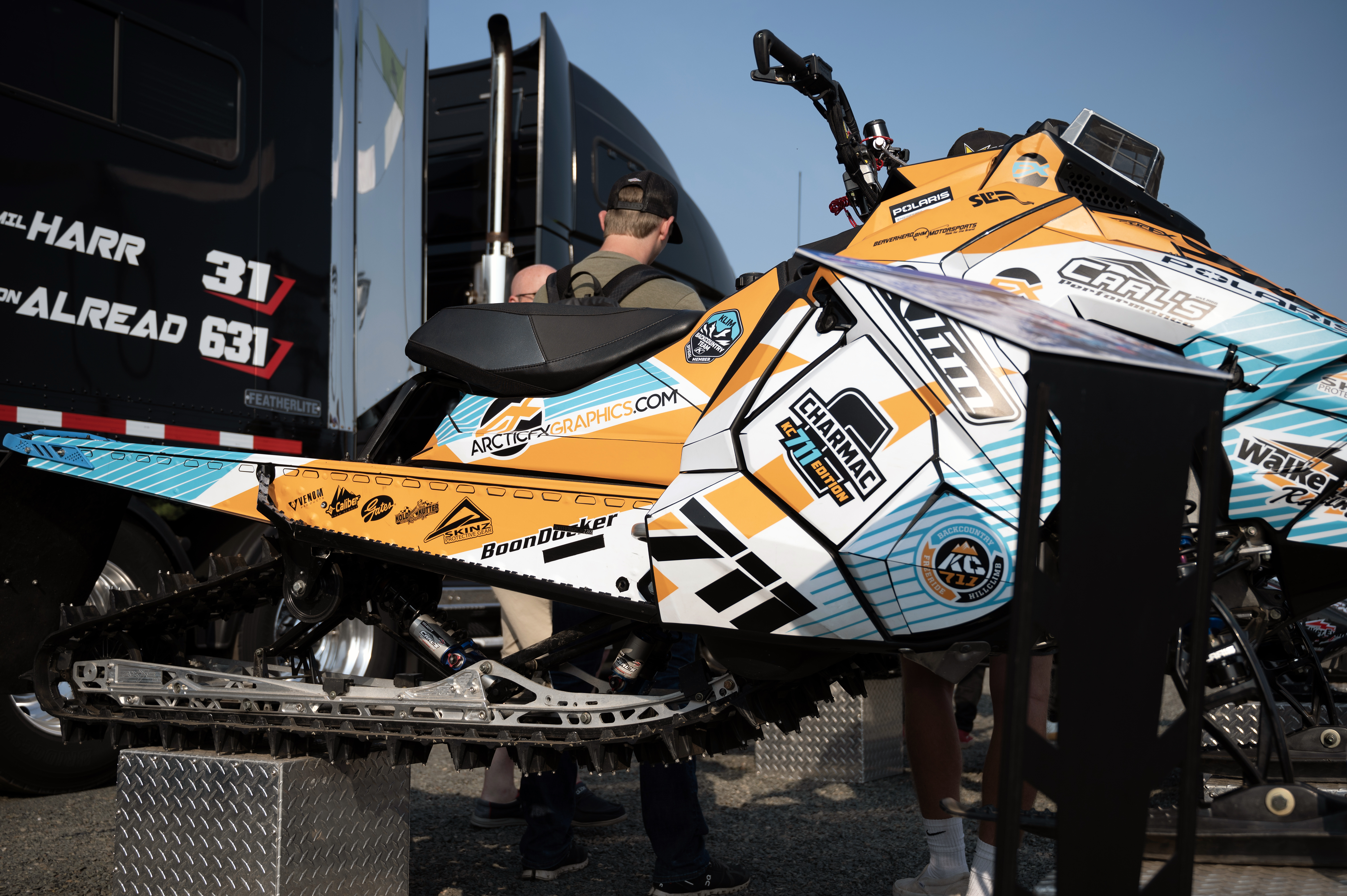 A Polaris Axys Mountain snowmobile with a orange, white, and blue Curtis Ascent custom vinyl wrap.