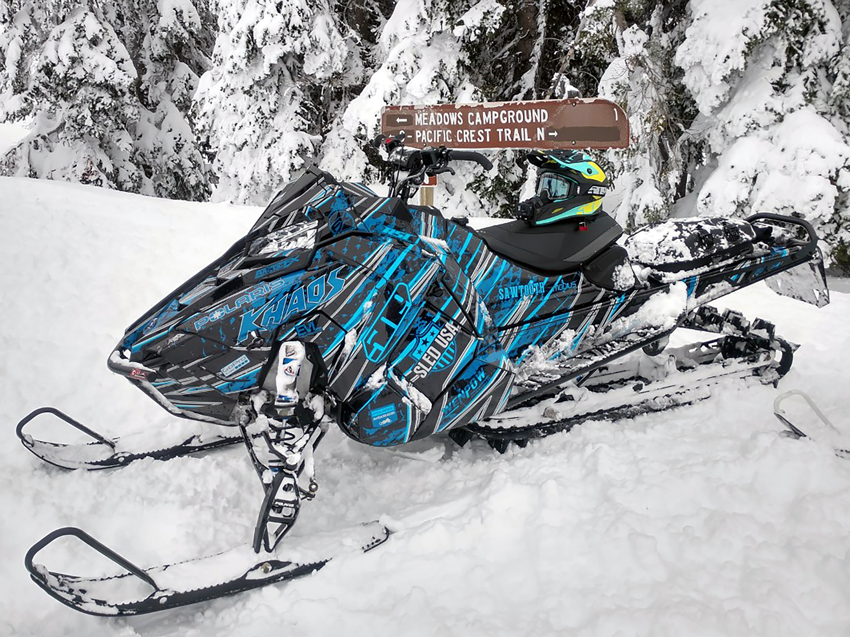 A Polaris Axys Mountain snowmobile with a black, gray, and blue Dangerzone custom vinyl wrap.