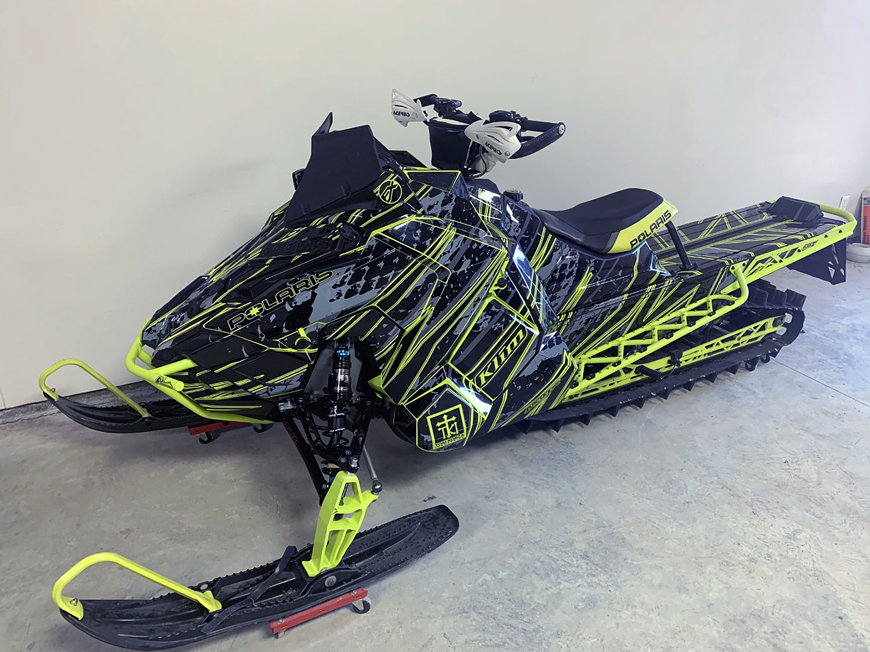 A Polaris Axys Mountain snowmobile with a lime squeeze, gray, and black Dangerzone custom vinyl wrap.