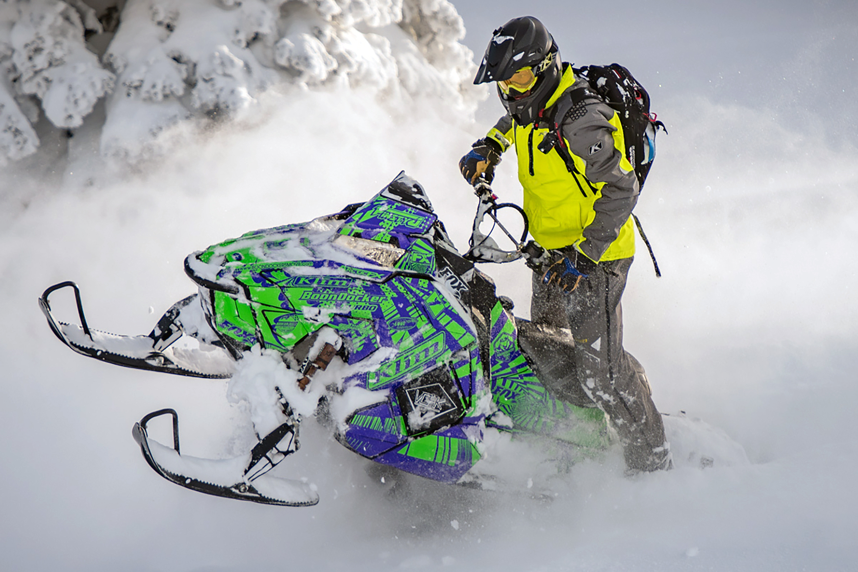 A Polaris Axys Mountain snowmobile with a lime and purple Delirious custom vinyl wrap.