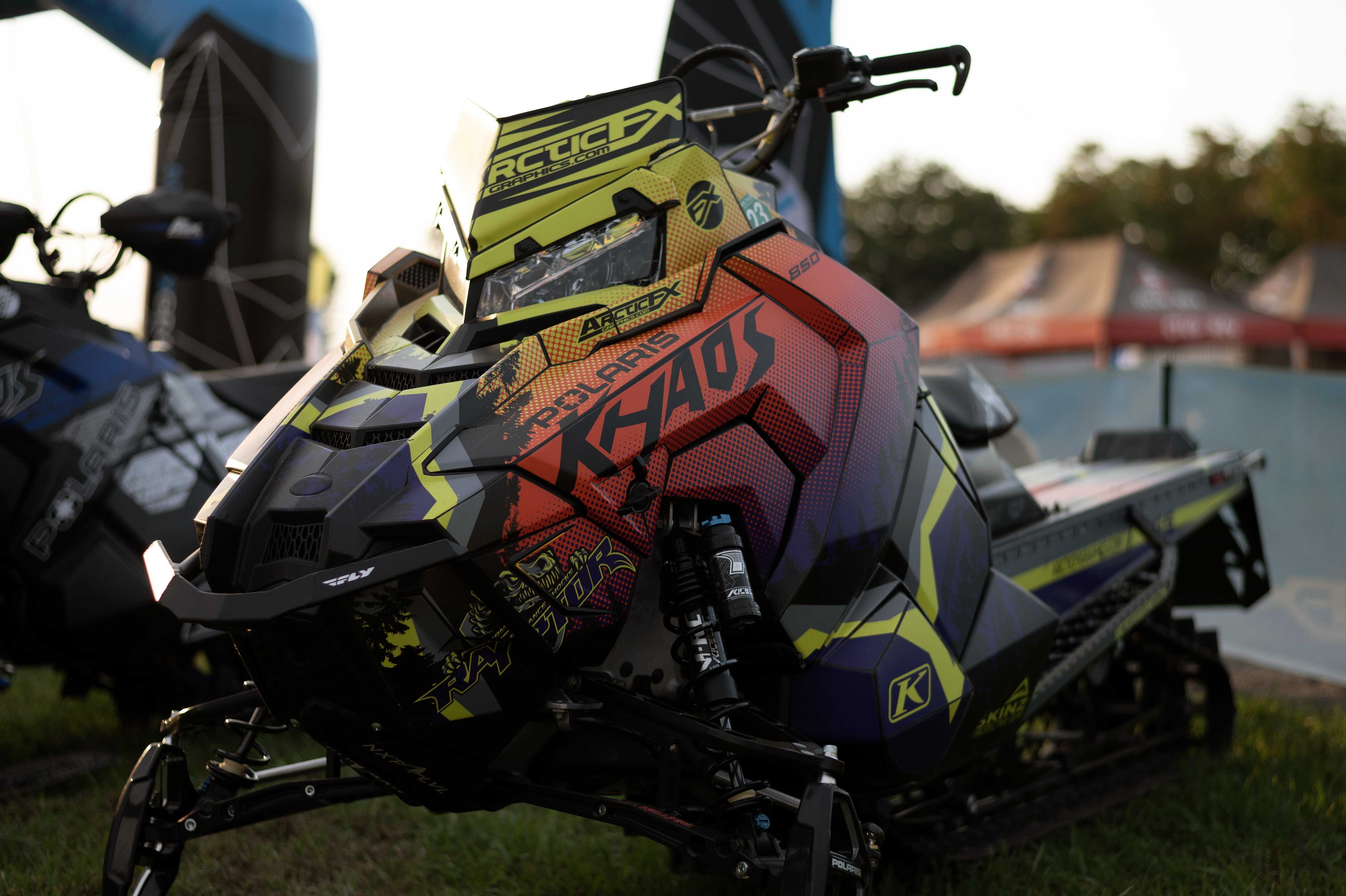 A Polaris Axys Mountain snowmobile with a lime squeeze, orange, and purple Entz Elevate custom vinyl wrap.