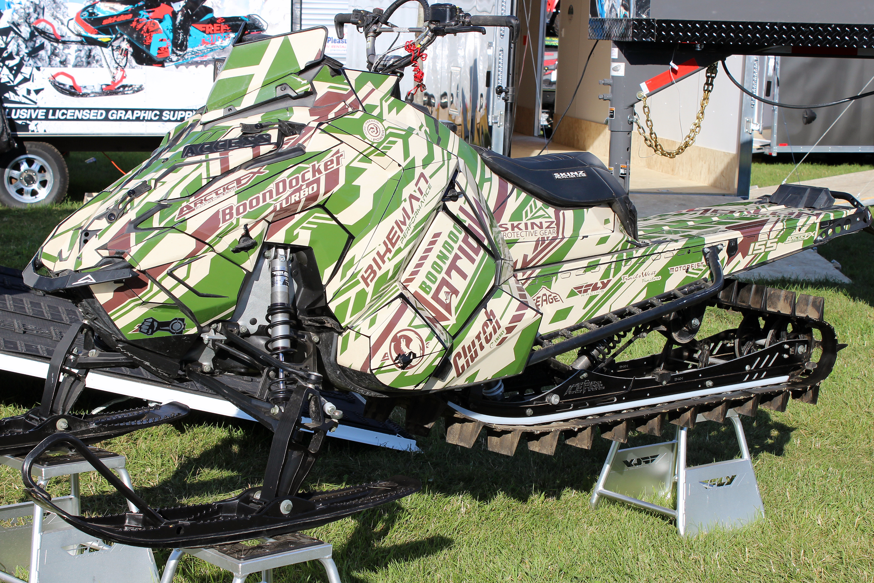 A Polaris Axys Mountain snowmobile with a green, tan, and brown Evasion custom vinyl wrap.