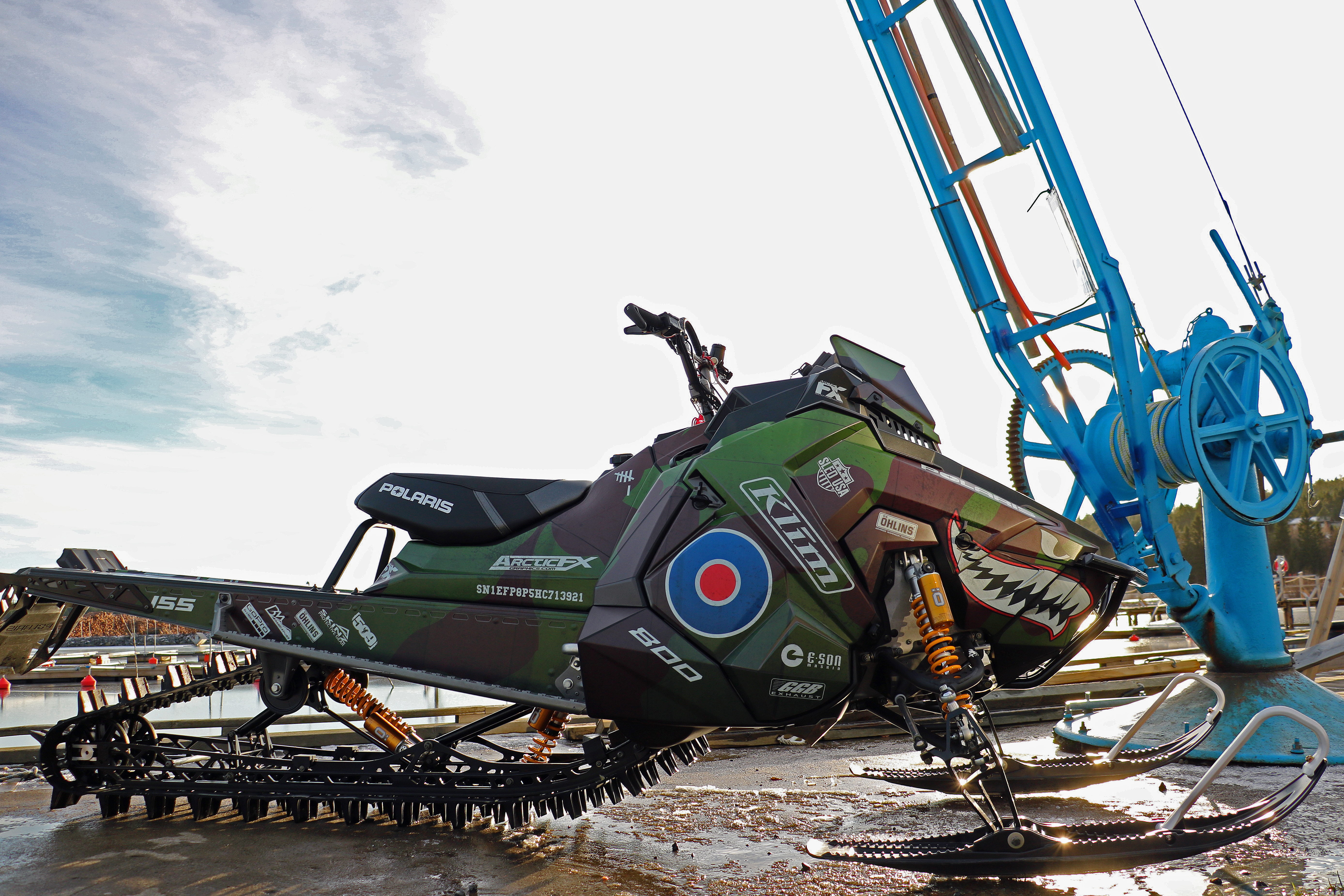 A Polaris Axys Mountain snowmobile with a green, brown, and red Flying Sharks Plane custom vinyl wrap.