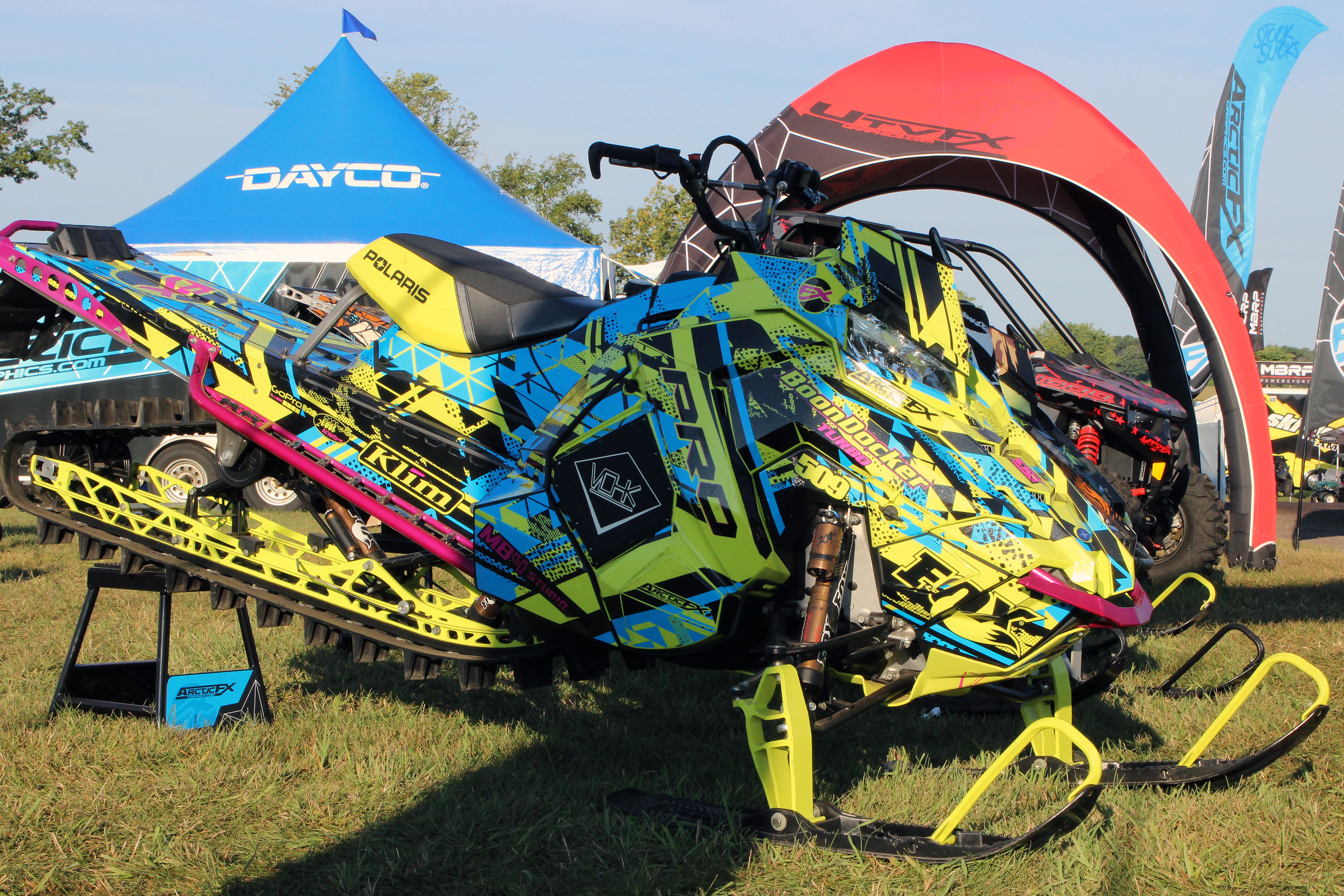 A Polaris Axys Mountain snowmobile with a lime squeeze, blue, and black MB4 Trifecta custom vinyl wrap.