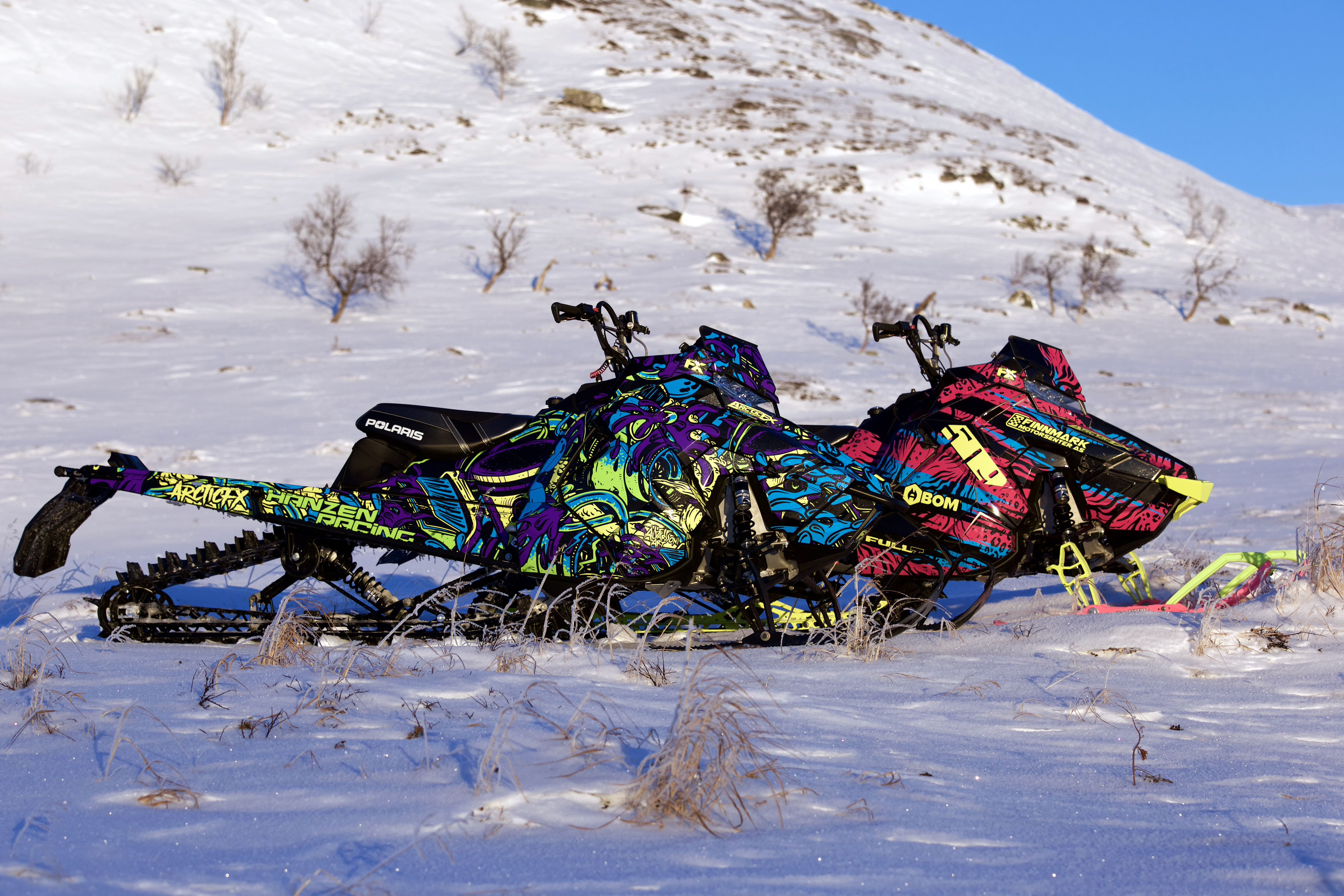 A Polaris Axys Mountain snowmobile with a lime squeeze, purple, blue, and black Onasch Fueled custom vinyl wrap.