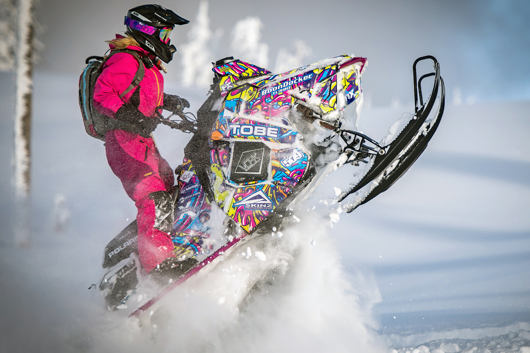 A Polaris Axys Mountain snowmobile with a lime squeeze, purple, blue, and pink Onasch Fueled custom vinyl wrap.