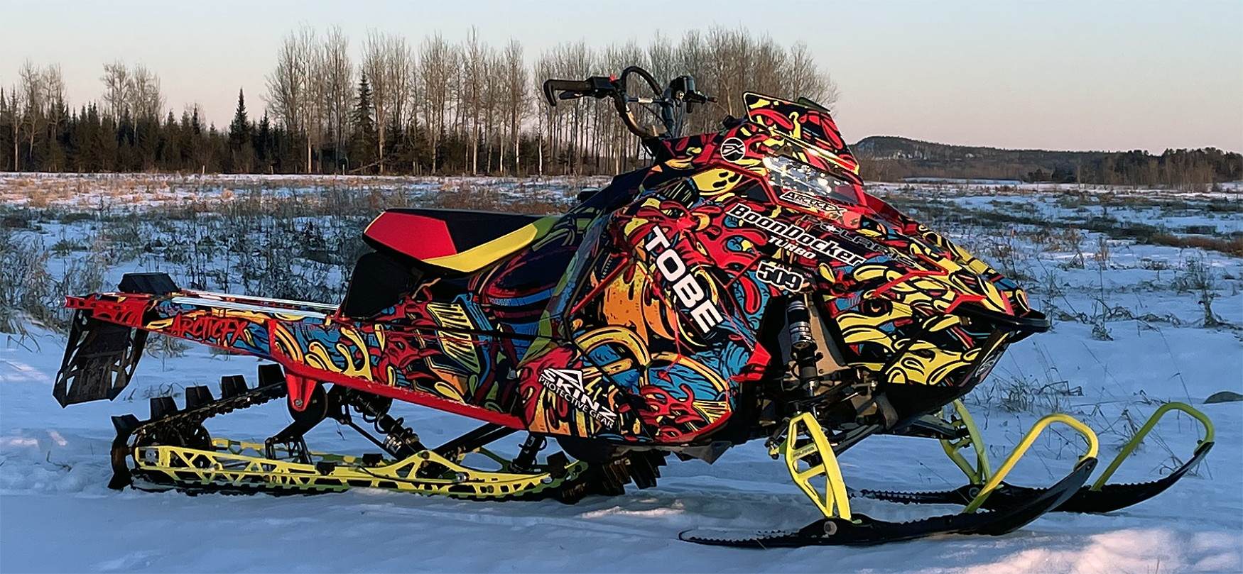 A Polaris Axys Mountain snowmobile with a lime squeeze, red, and blue Onasch Fueled custom vinyl wrap.
