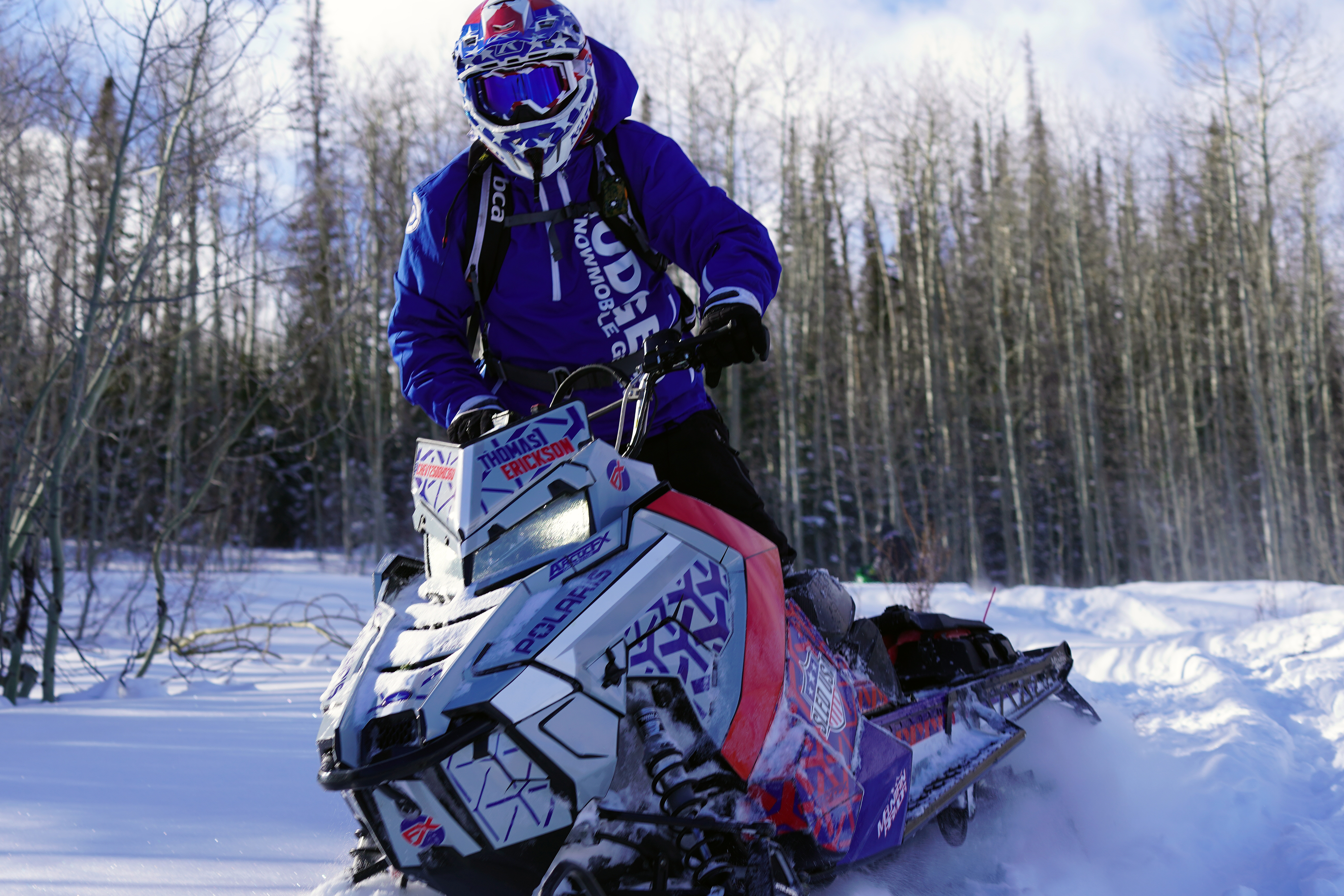 A Polaris Axys Mountain snowmobile with a gray, blue, and red Fusion custom vinyl wrap.