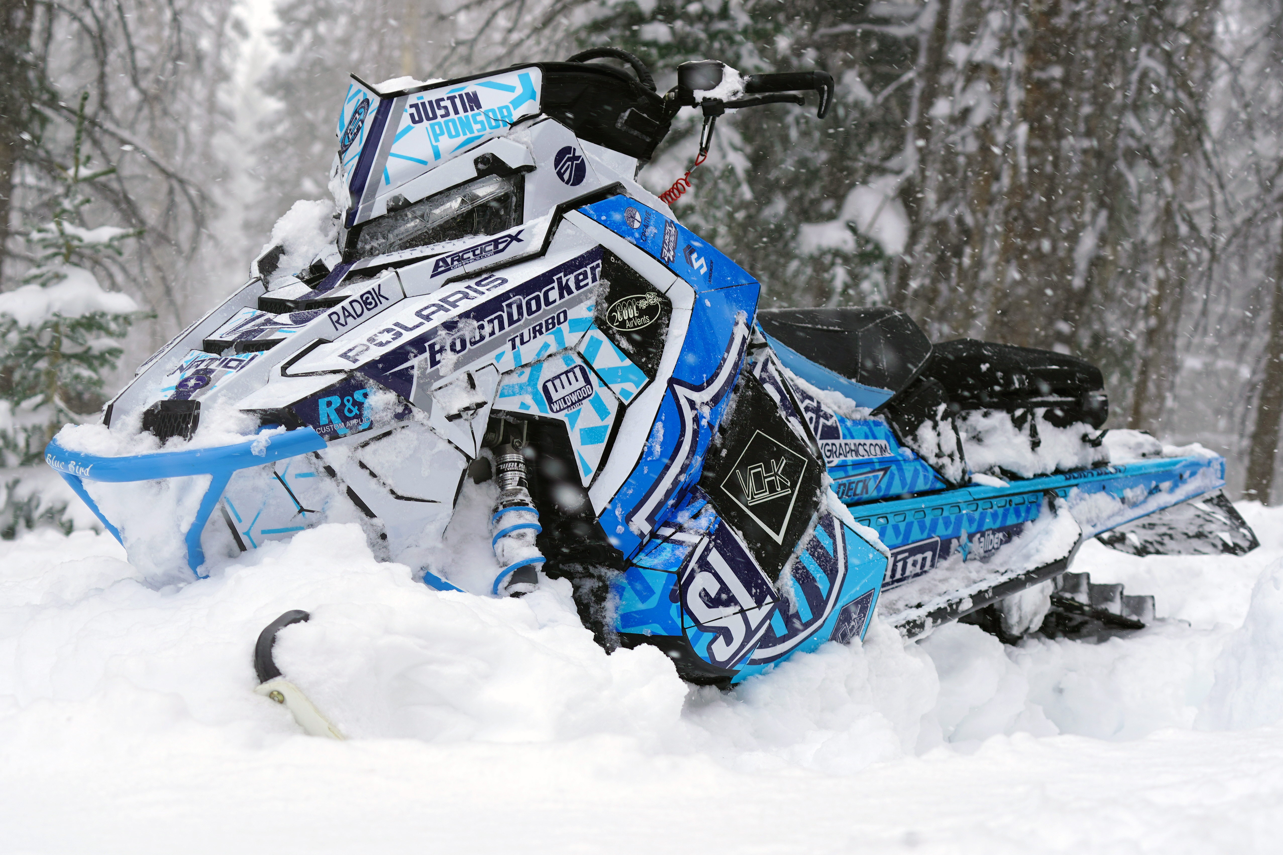 A Polaris Axys Mountain snowmobile with a white, blue, and black Fusion custom vinyl wrap.