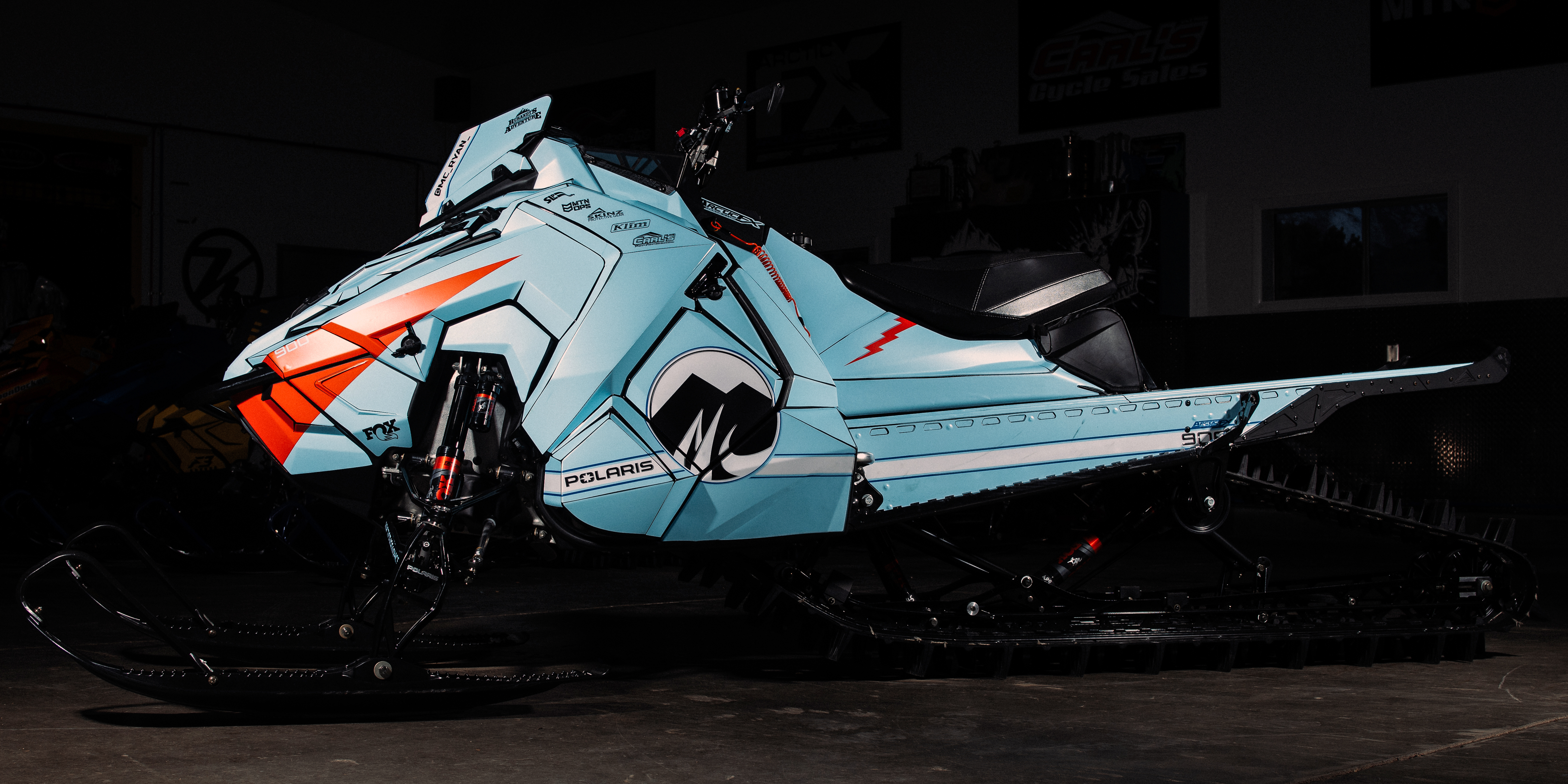 A Polaris Axys Mountain snowmobile with a white, blue, and orange GT40 race car custom vinyl wrap.