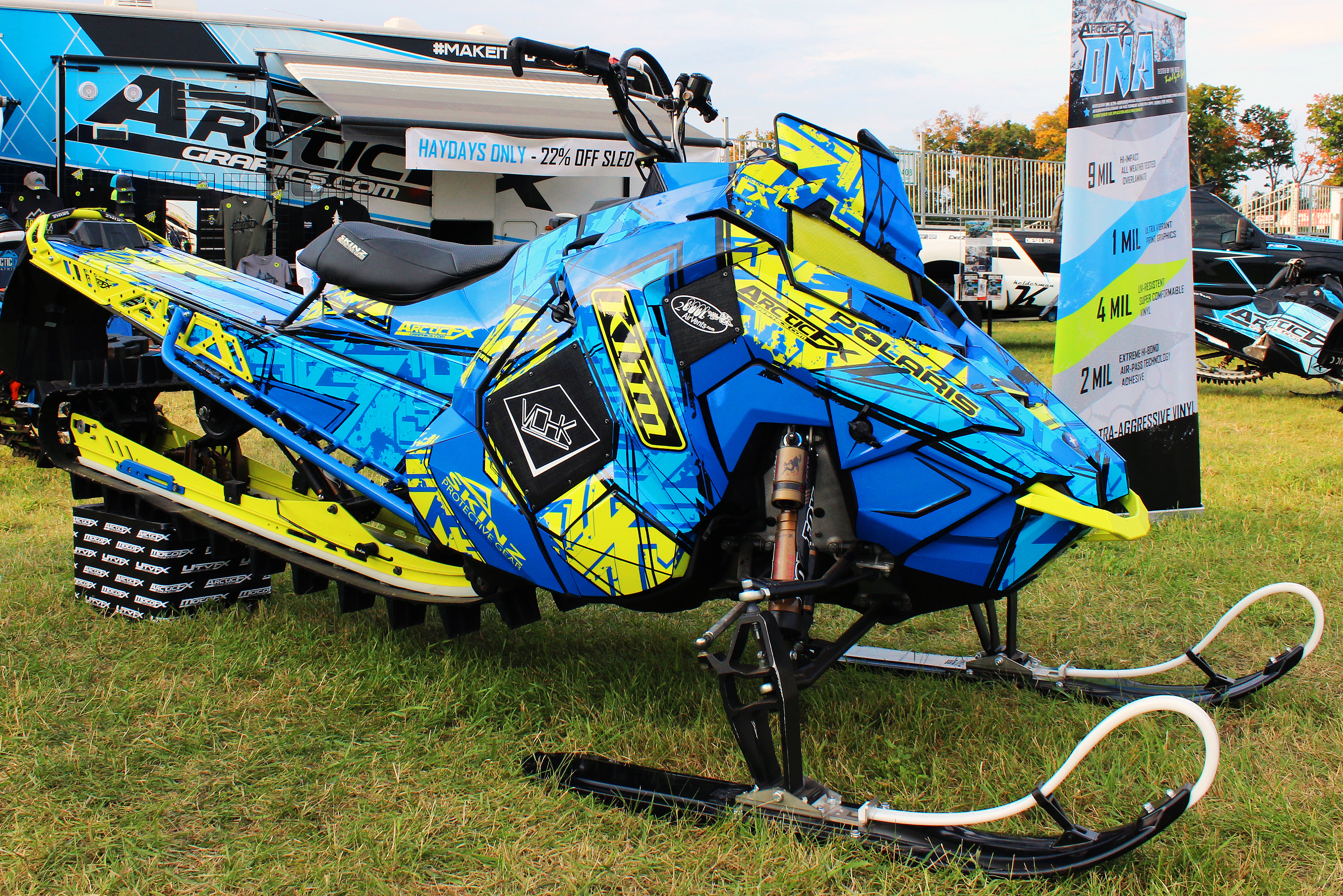 A Polaris Axys Mountain snowmobile with a lime squeeze, blue, and black Havoc custom vinyl wrap.