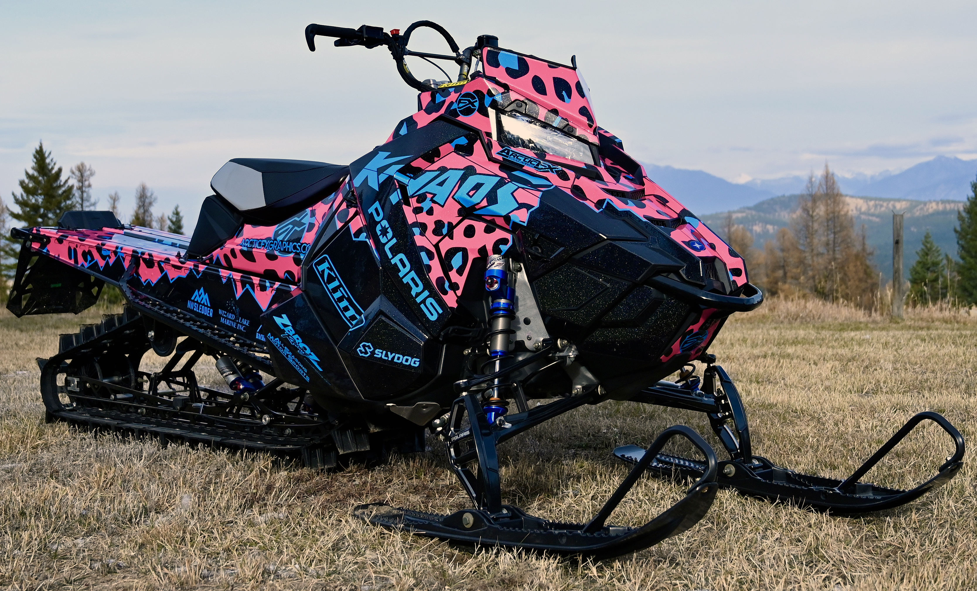 A Polaris Axys Mountain snowmobile with a pink, blue, and black Hockley Cheetah Custom custom vinyl wrap.