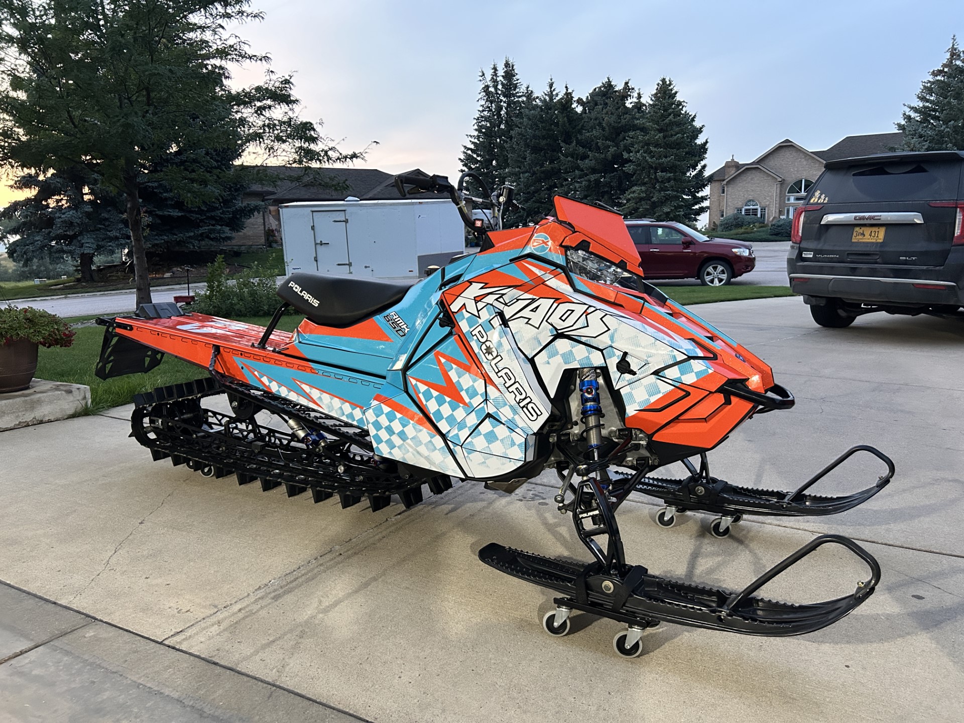A Polaris Axys Mountain snowmobile with a white, ice blue, and orange KC Ignition custom vinyl wrap.
