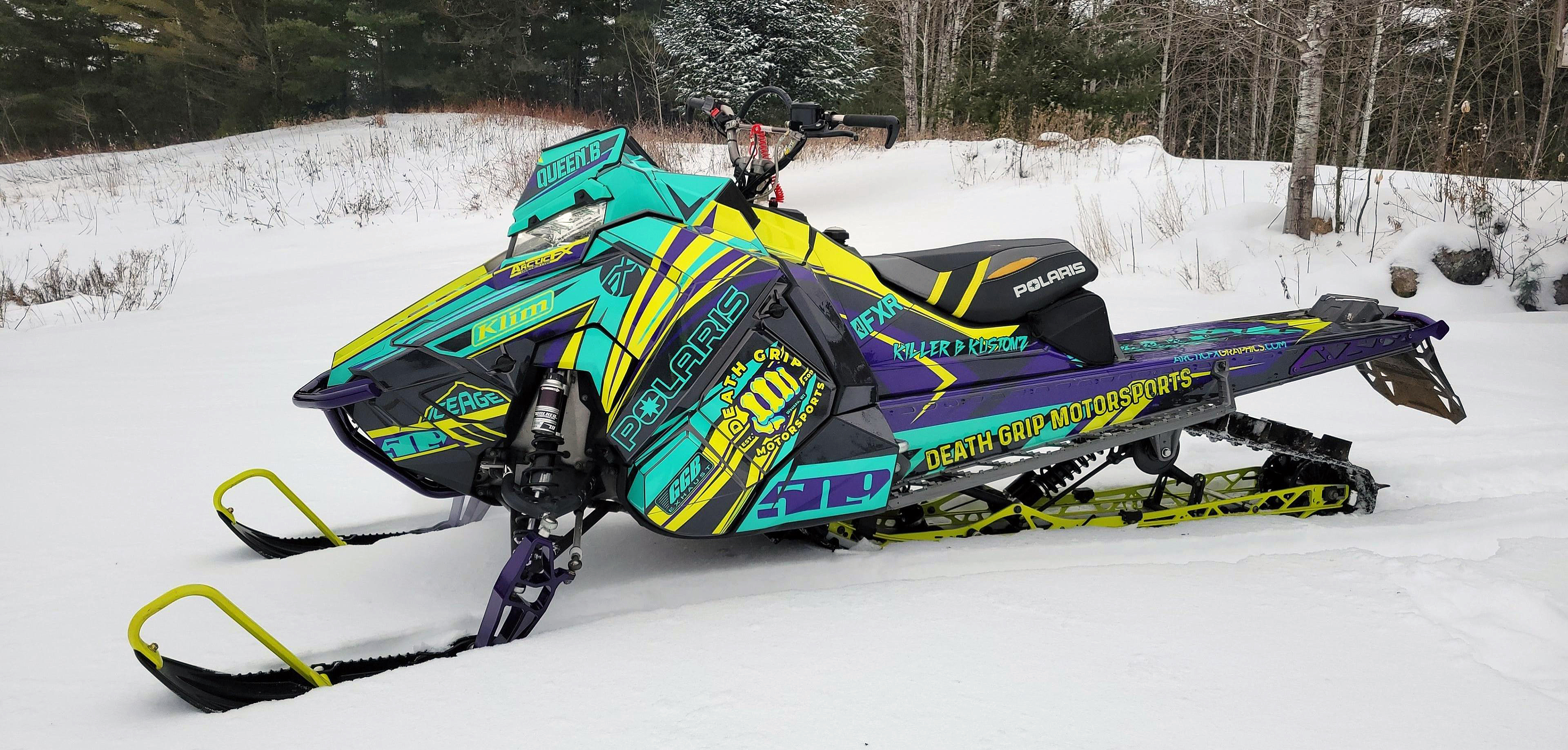 A Polaris Axys Mountain snowmobile with a aqua, black, and lime squeeze Kesterke Adrenaline custom vinyl wrap.