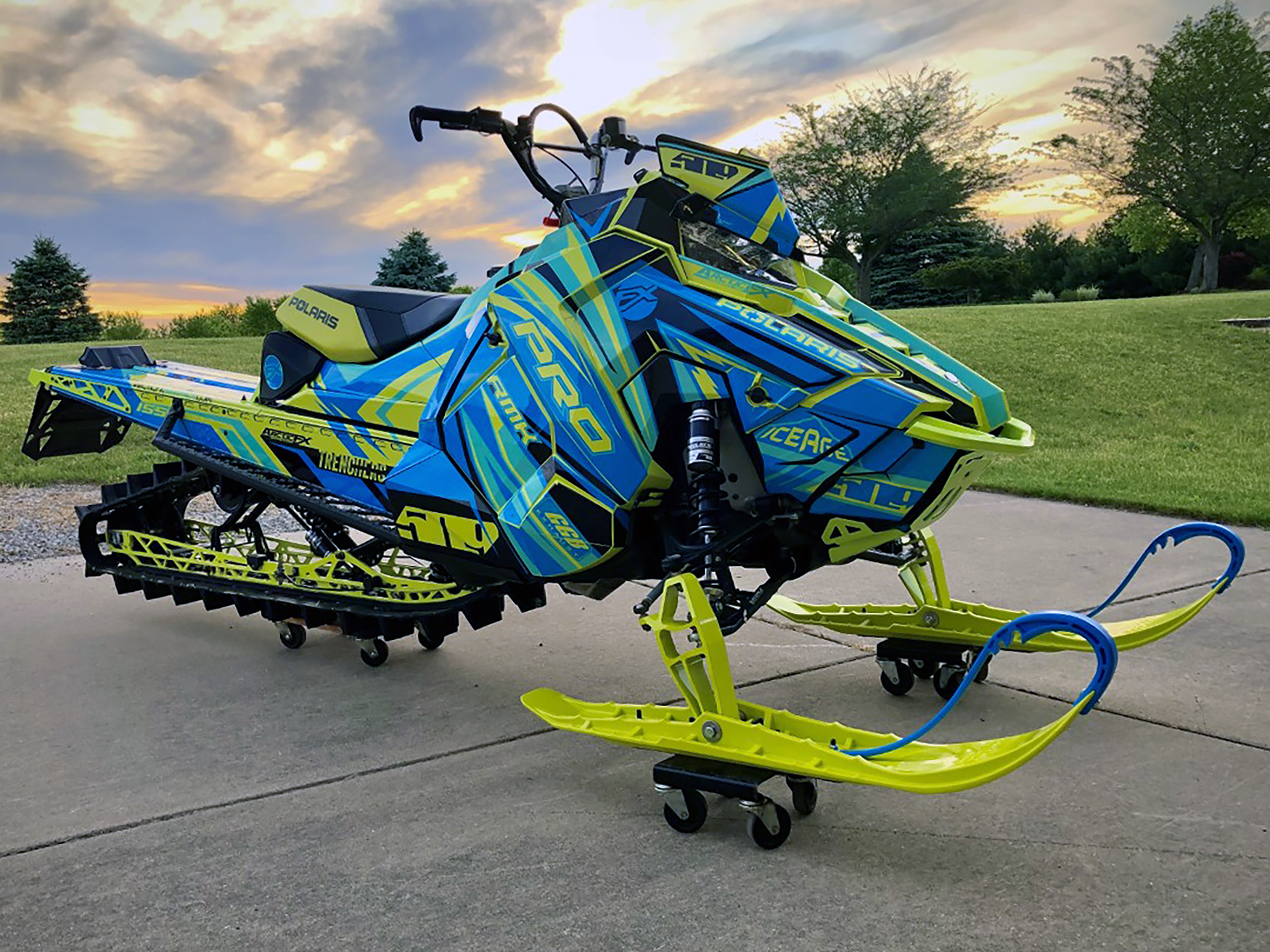 A Polaris Axys Mountain snowmobile with a blue, black, and lime squeeze Kesterke Adrenaline custom vinyl wrap.