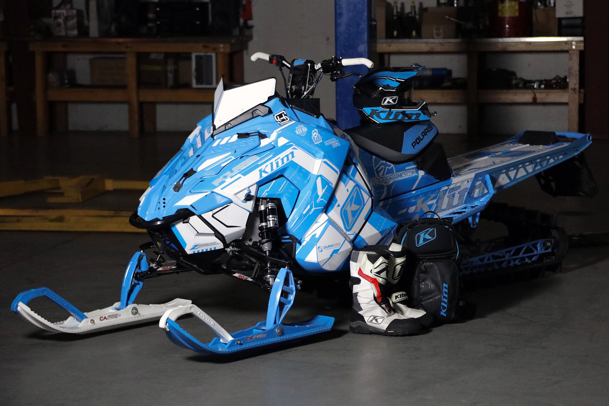 A Polaris Axys Mountain snowmobile with a black, white, and blue Klim Recoil custom vinyl wrap.