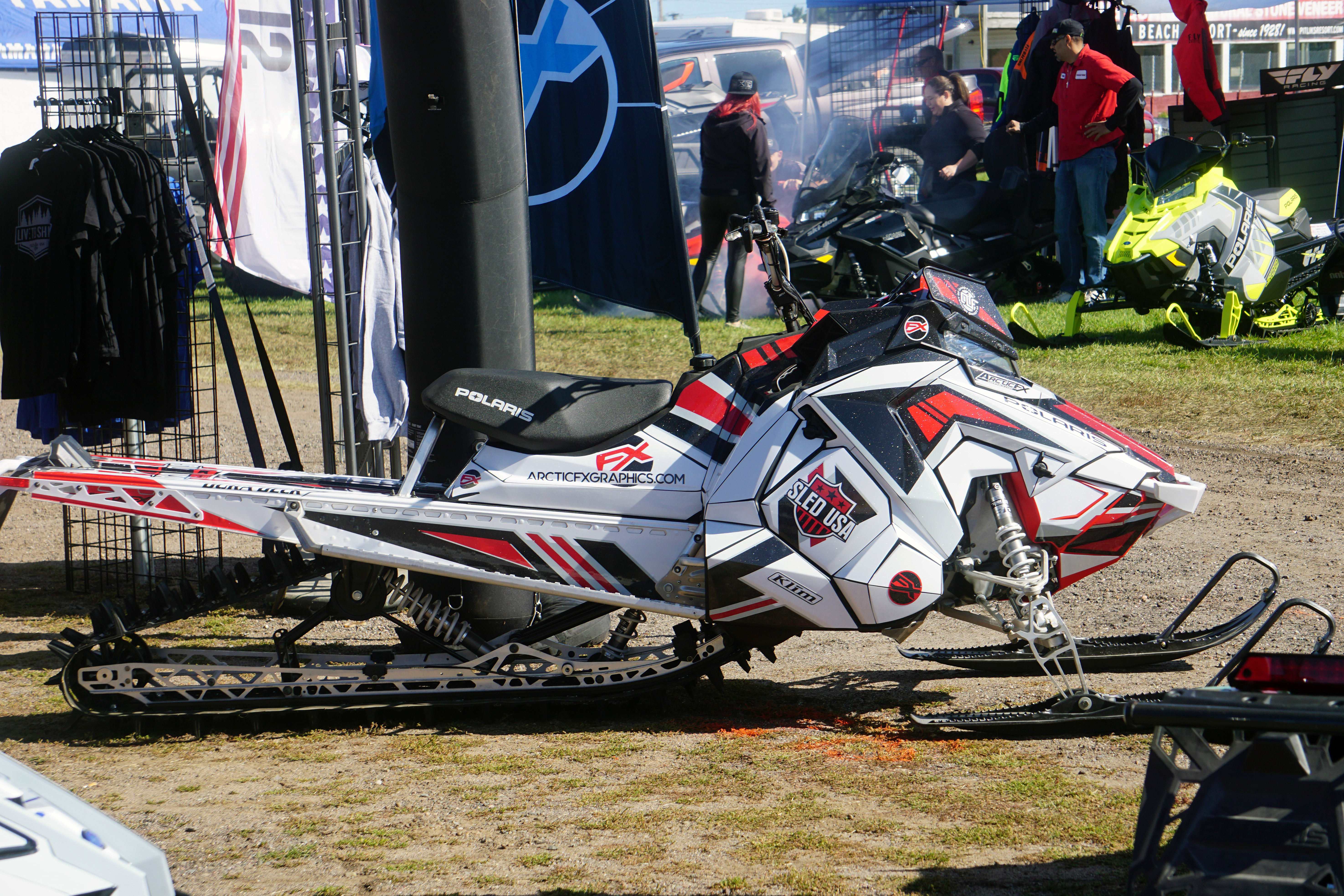 A Polaris Axys Mountain snowmobile with a black, red, and white Quantum custom vinyl wrap.