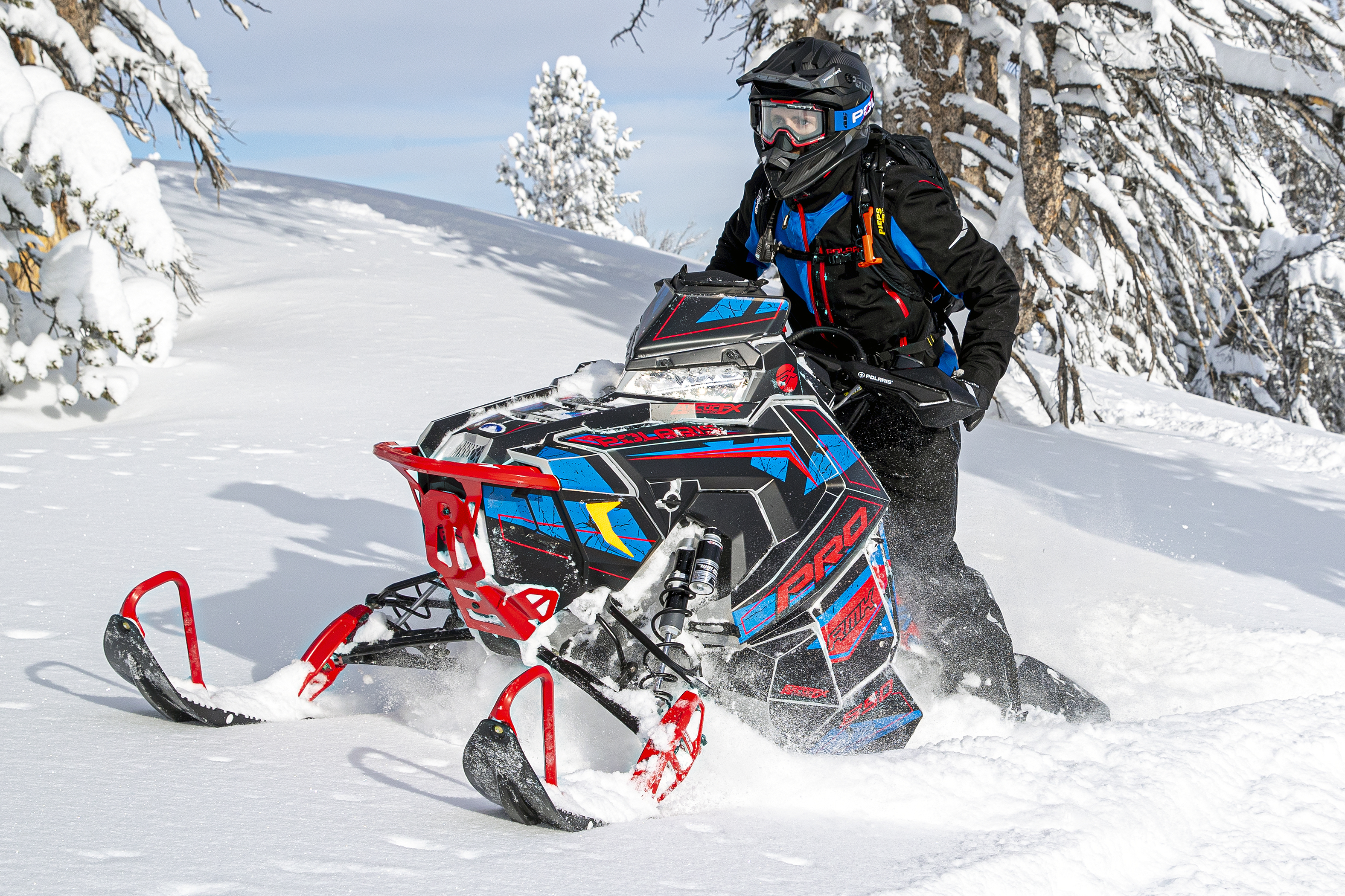 A Polaris Axys Mountain snowmobile with a black, red, and blue Rogue custom vinyl wrap.