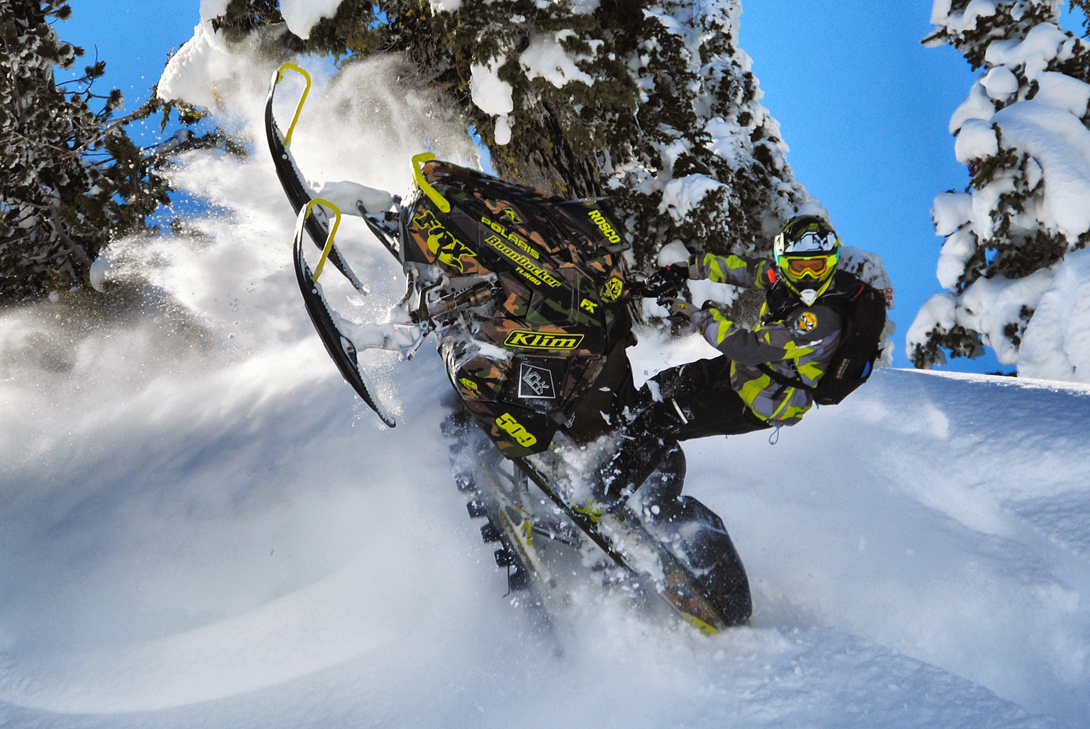 A Polaris Axys Mountain snowmobile with a army green, lime, and brown RR Camo custom vinyl wrap.