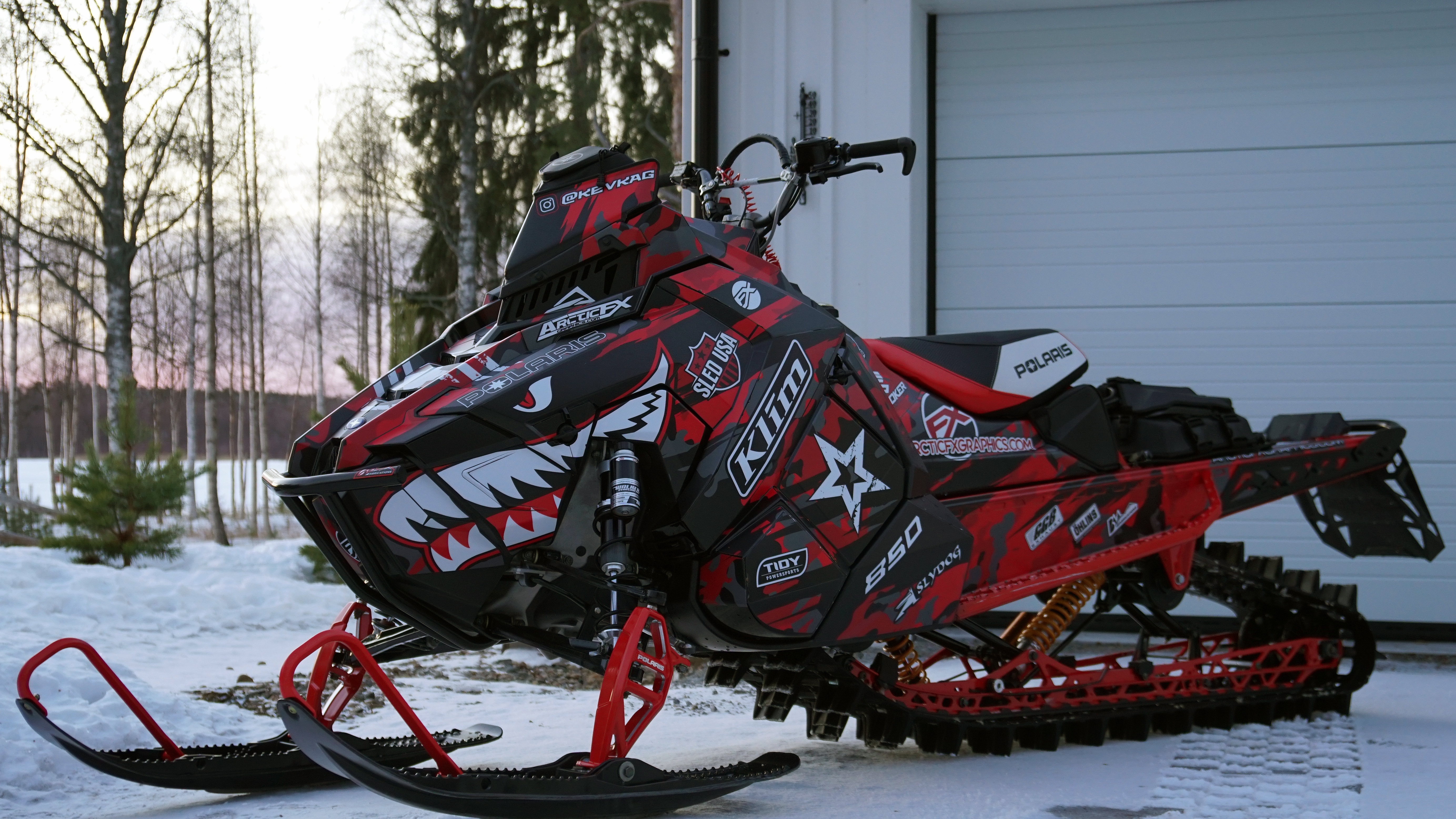 A Polaris Axys Mountain snowmobile with a red, black, and gray flying sharks RR Camo custom vinyl wrap.