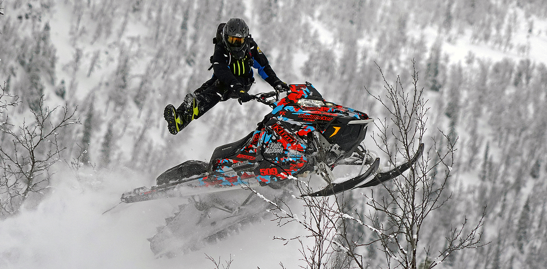 A Polaris Axys Mountain snowmobile with a blue, black, and red RR Camo custom vinyl wrap.
